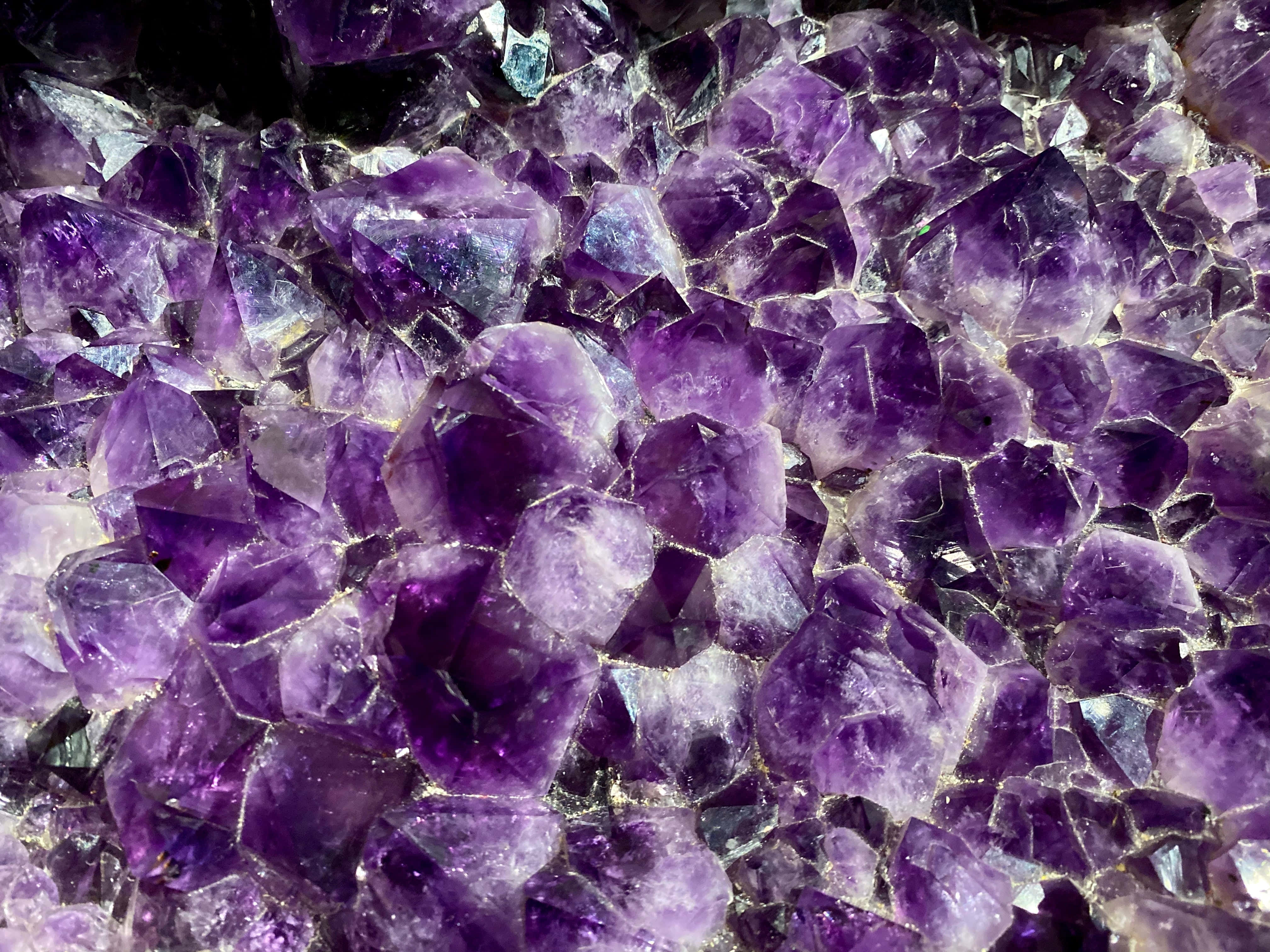 Gemstone 桌布 壁紙 — 閃爍紫色紫水晶晶體的近距離特寫，具有銳利的刻面和深紫羅蘭色調。