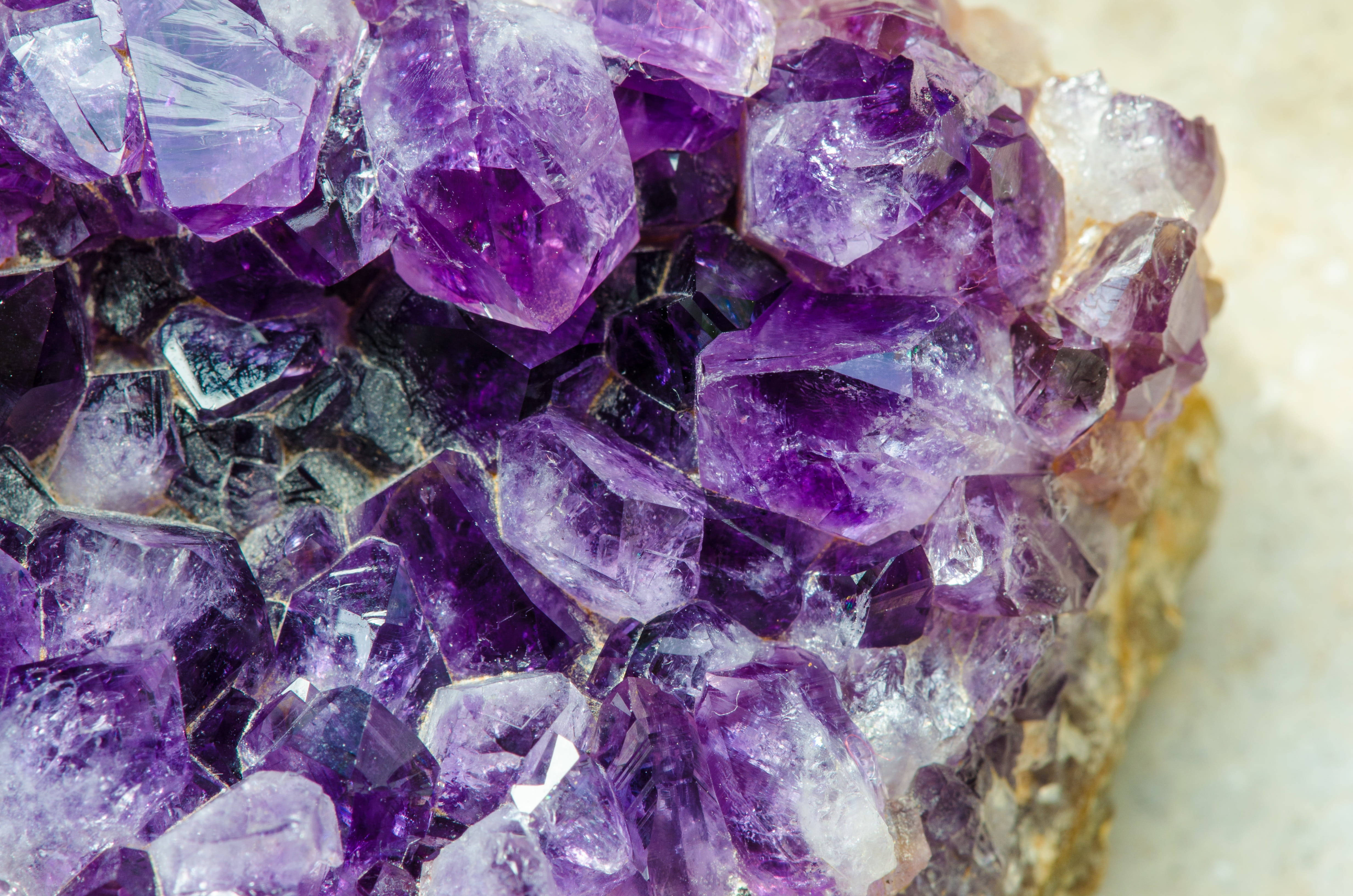 紫水晶 桌布 壁紙 — 閃爍紫色紫水晶晶體的近距離特寫，晶體聚集在一起，具有銳利的刻面和半透明色調。