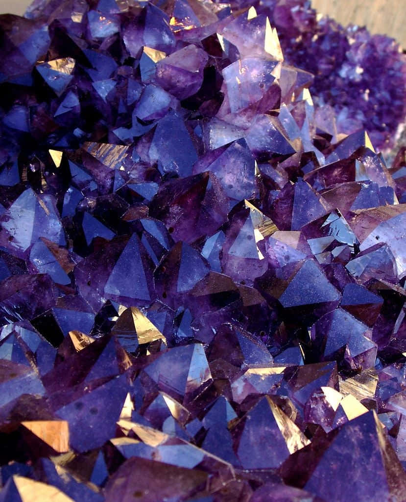 紫水晶 桌布 壁紙 — 閃爍紫色紫水晶晶體的近距離特寫，具有銳利的刻面，捕捉金色光線。