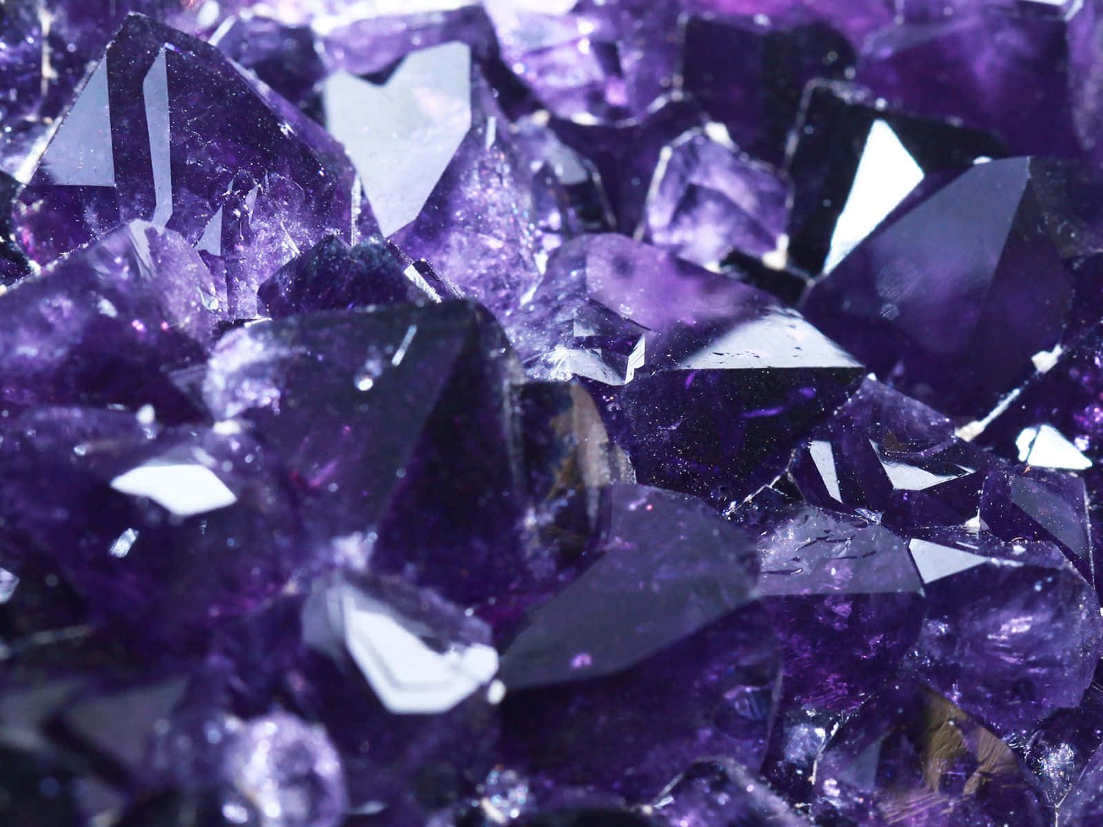 紫水晶 桌布 壁紙 — 閃爍紫色紫水晶晶體的近距離特寫，具有鋒利的刻面，捕捉明亮光線。