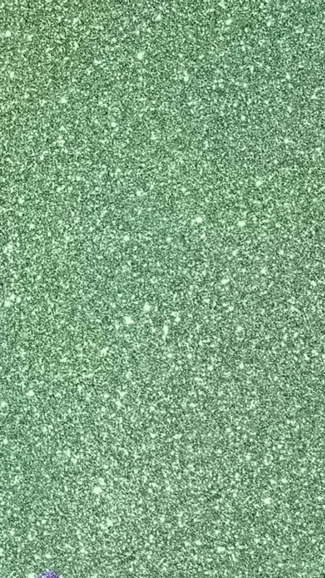 Green Glitter 桌布 壁紙 — 閃爍綠色亮片的特寫，帶有分散的明亮斑點，營造出閃閃發光的紋理表面。