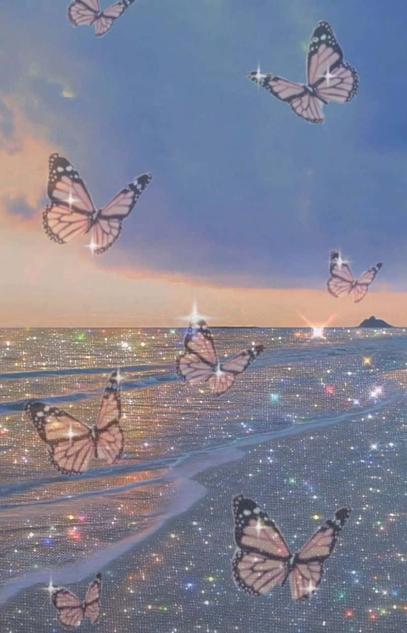 Glitter Butterfly 桌布 壁紙 — 閃爍翅膀的蝴蝶在柔和的藍天下，於日落時分在閃閃發光的海洋上翩翩起舞。