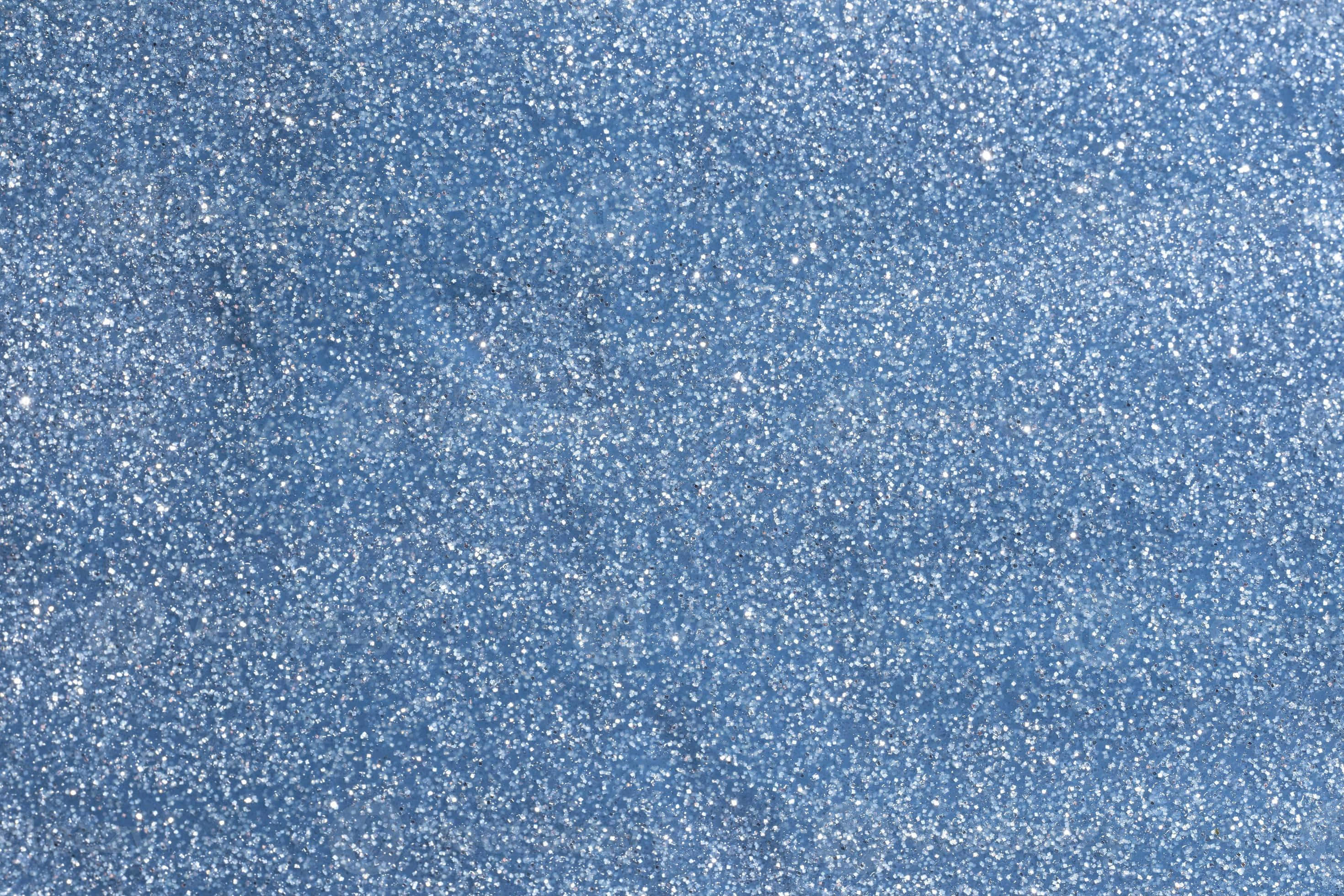 Periwinkle Blue 桌布 壁紙 — 閃爍藍色亮粉的特寫，帶有散落的銀色閃光，營造出有紋理且閃亮的表面。