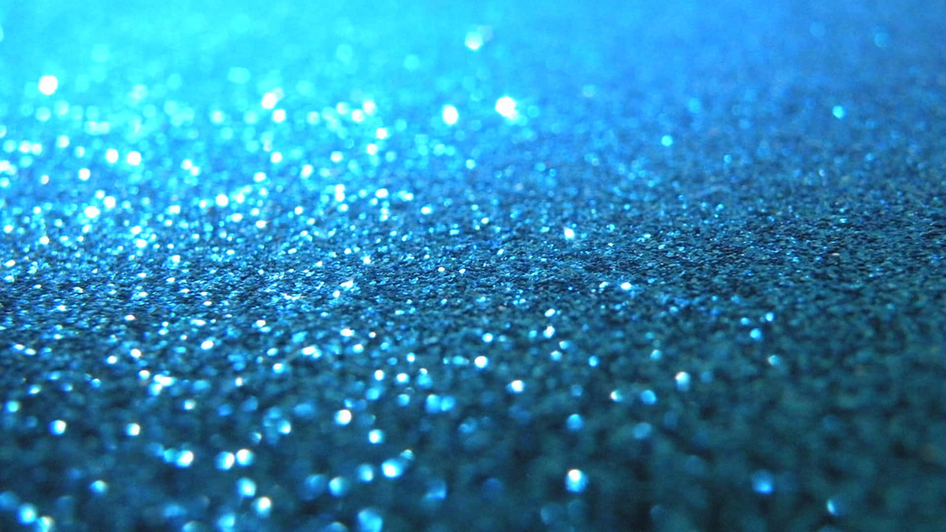 Blue Sparkle 桌布 壁紙 — 閃爍藍色亮粉的特寫，散景高光營造出閃閃發光的紋理表面。