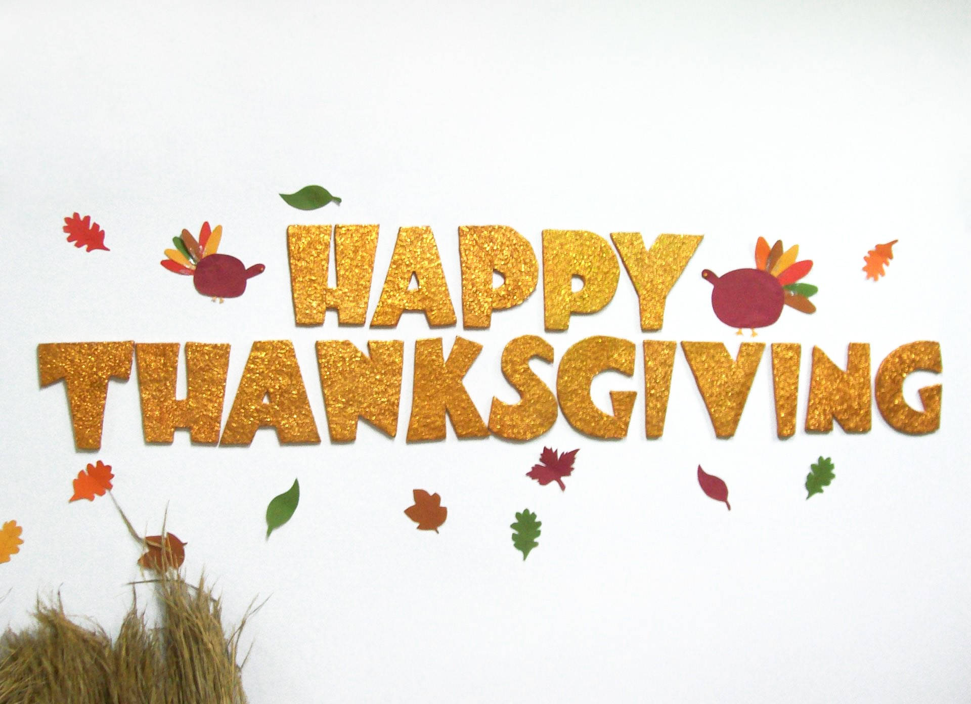 Cute Thanksgiving 桌布 壁紙 — 閃爍金色 'HAPPY THANKSGIVING' 字母，周圍環繞著紙火雞和秋葉，背景為白色。