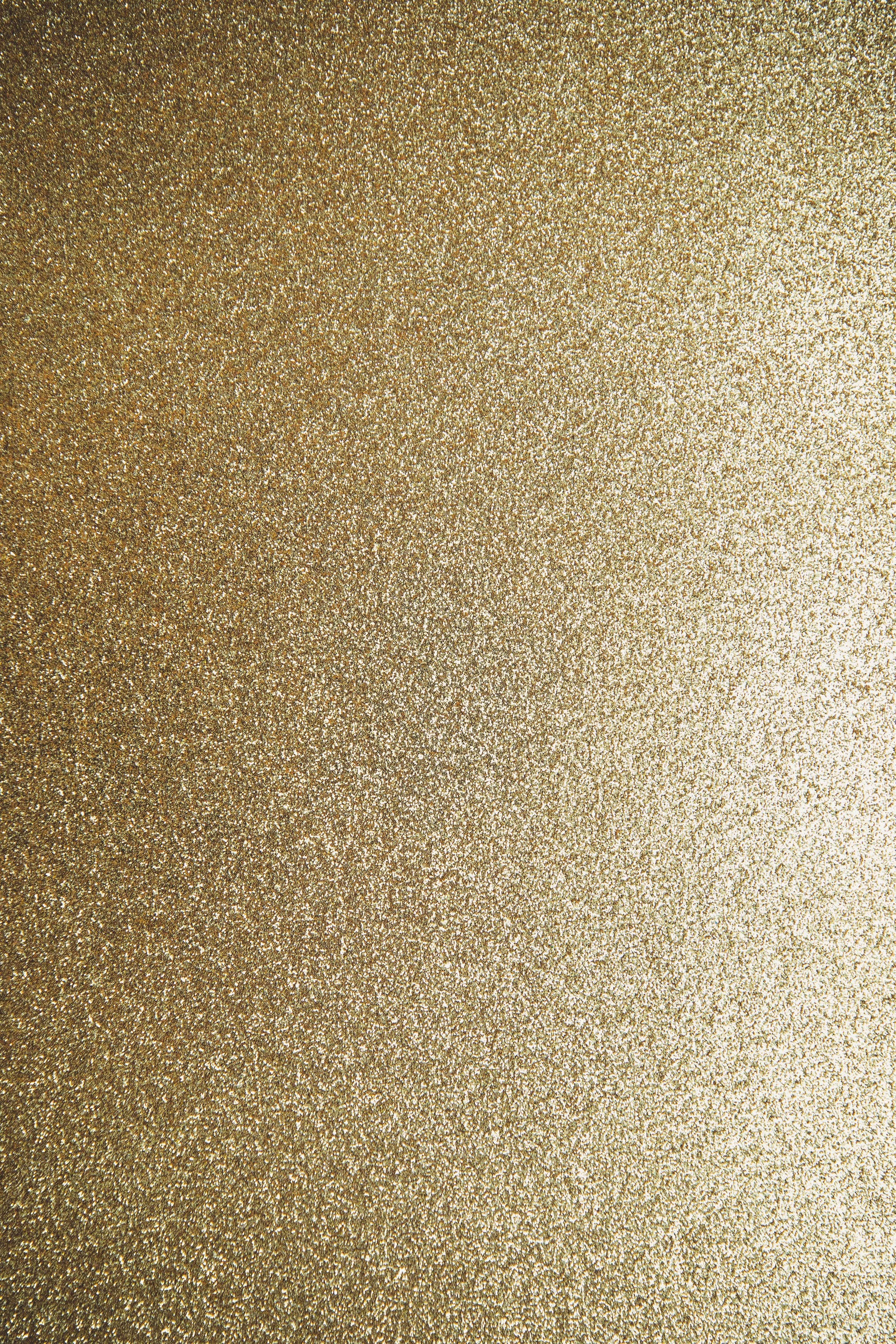 Gold Glitter 桌布 壁紙 — 閃爍金色亮粉紋理的近距離特寫，表面帶有微妙的漸變光線。