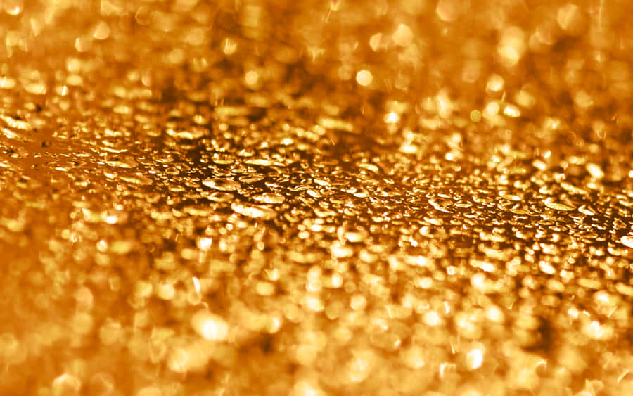 Shiny Gold 桌布 壁紙 — 閃爍金色亮粉顆粒捕捉光線的特寫，帶有柔和散景模糊效果。