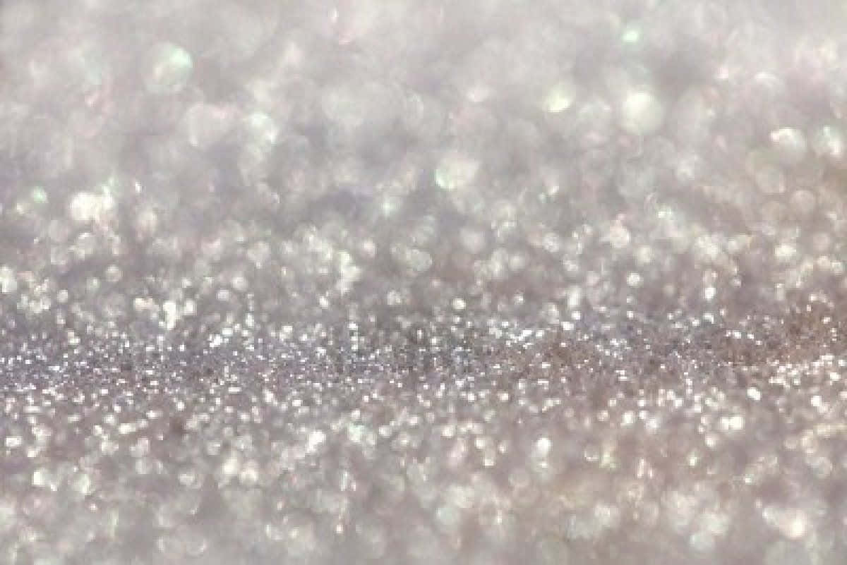 White Glitter 桌布 壁紙 — 閃爍銀色亮粉粒子的特寫，帶有柔和散景高光，營造出閃閃發光的紋理表面。