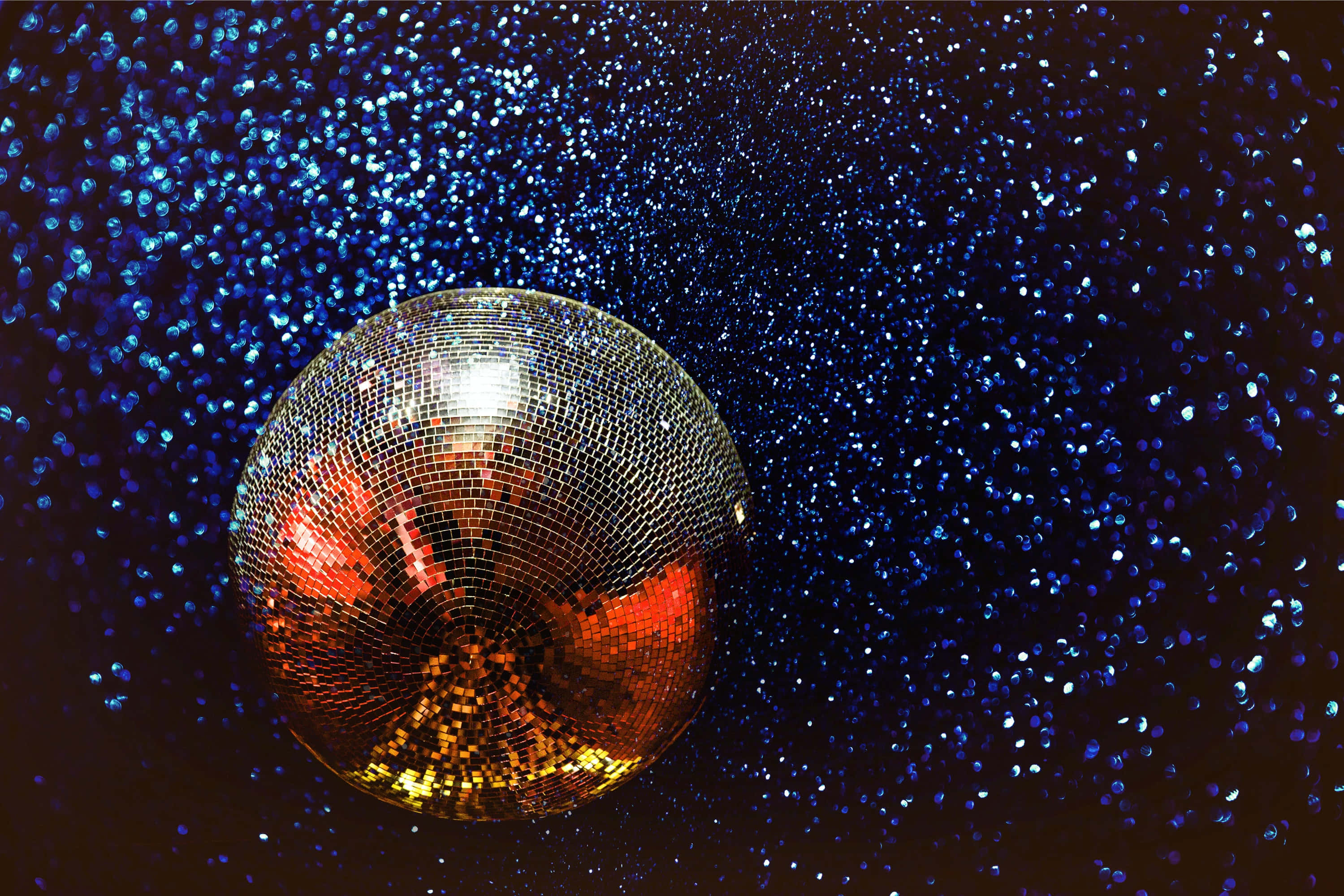 ball 桌布 壁紙 — 閃閃發光的迪斯科球在閃爍的藍色背景上反射出溫暖的燈光。