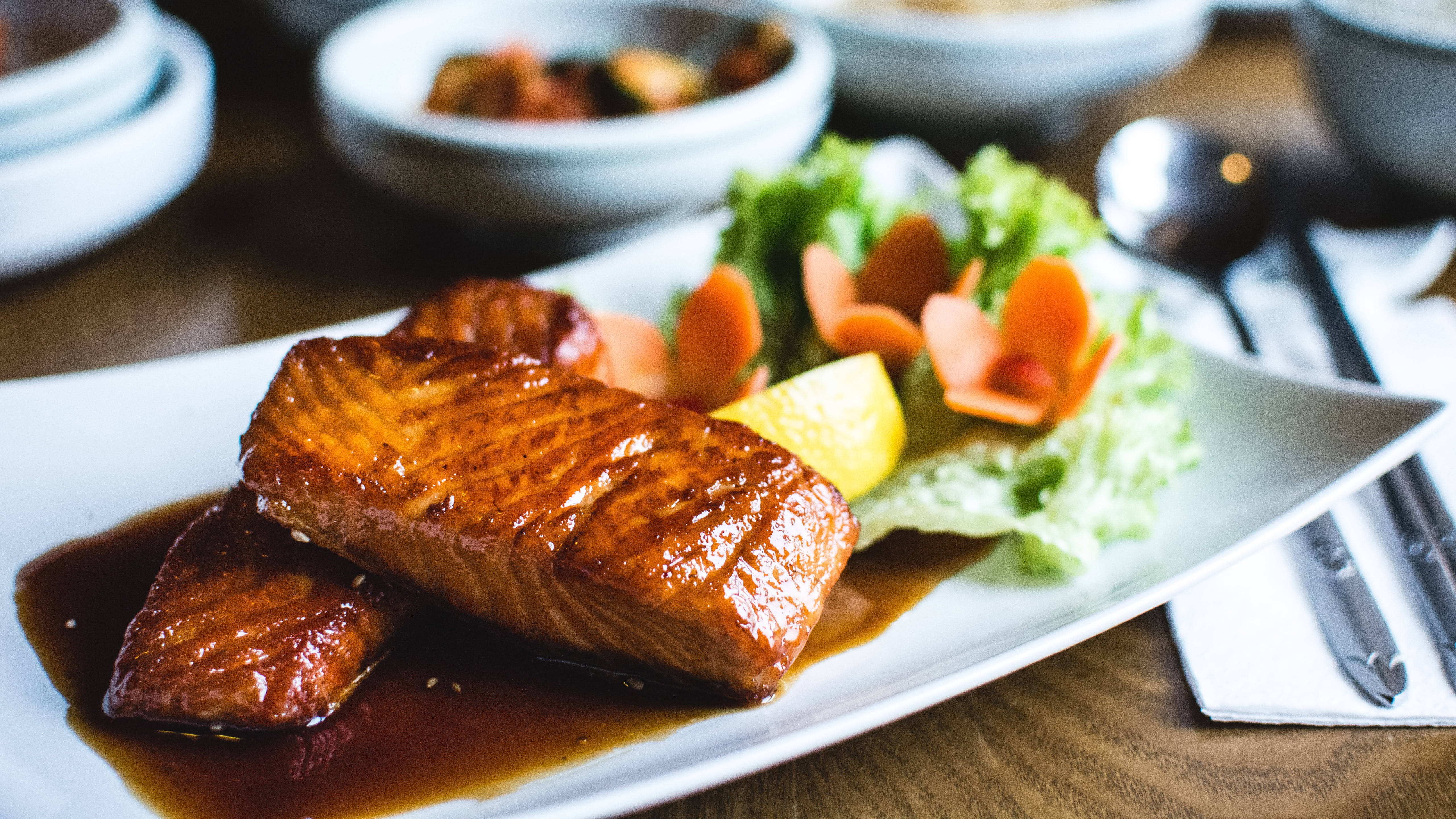 Delicious Food 桌布 壁紙 — 閃閃發光的釉面鮭魚片放在白色盤子上，旁邊是新鮮生菜和胡蘿蔔裝飾。