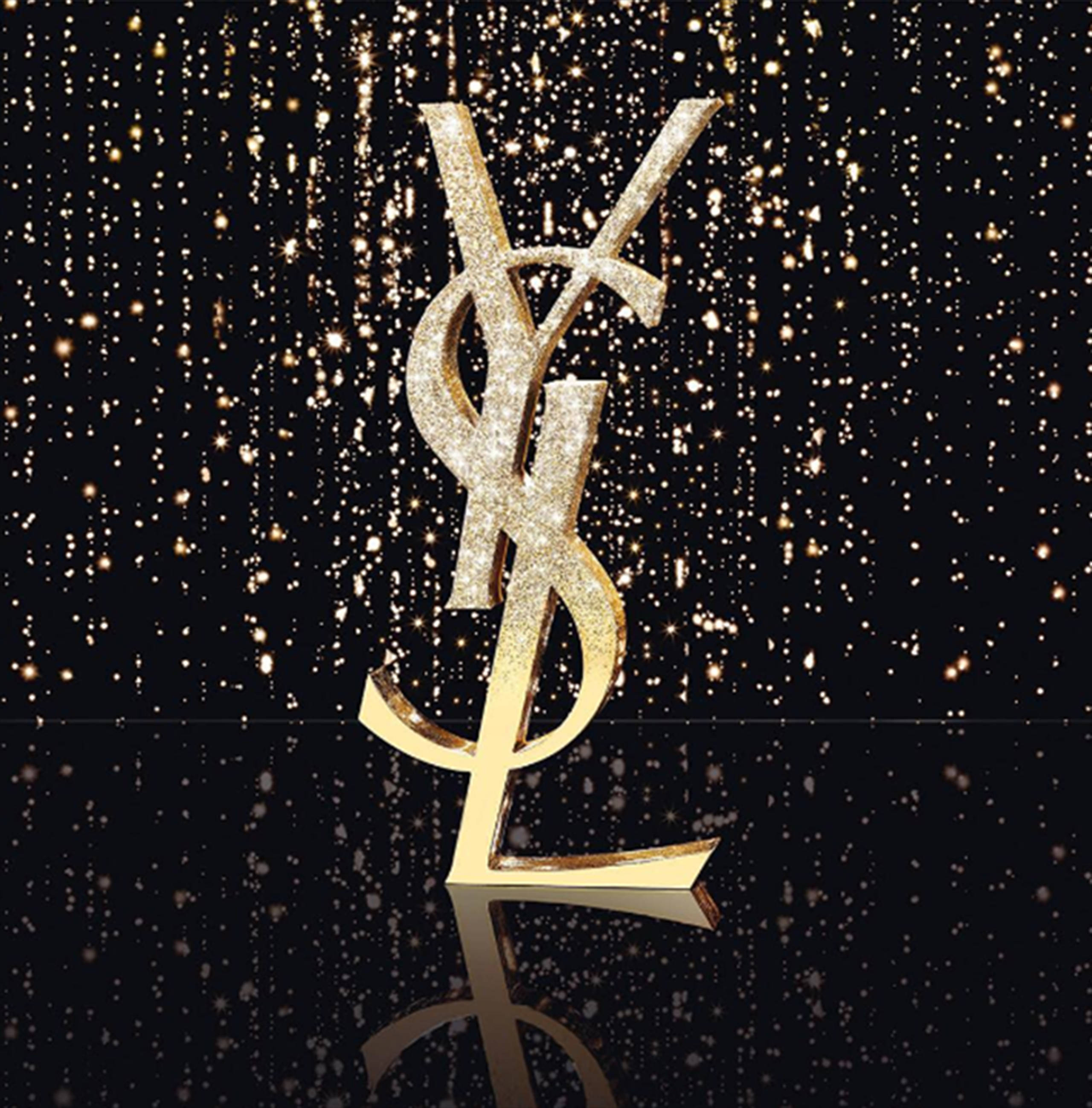 YSL 桌布 壁紙 — 閃閃發光的金色YSL標誌聳立在黑色背景上，背景灑滿了落下的金色閃粉及其下方的倒影。