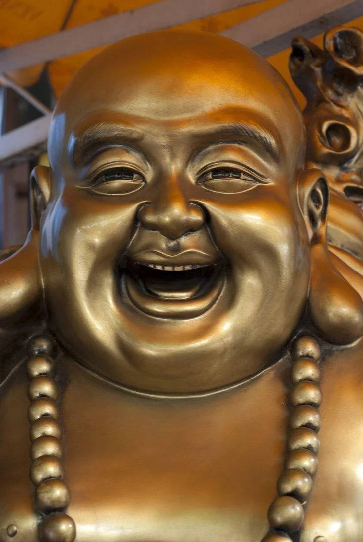 佛陀 桌布 壁紙 — 閃閃發光的金色笑佛雕像特寫，表情歡樂，戴著珠串項鍊。