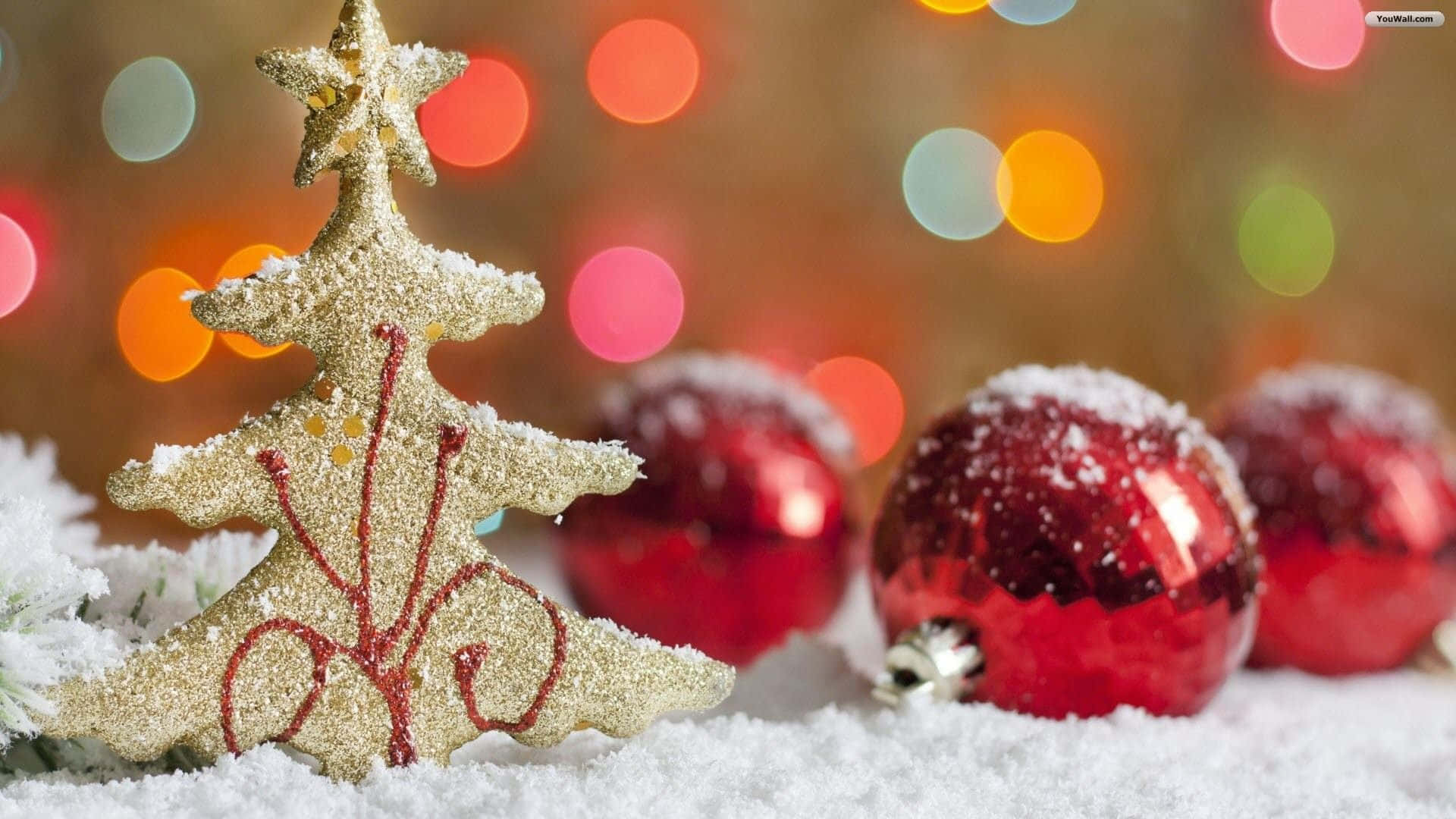 Christmas Ornament 桌布 壁紙 — 閃閃發光的金色聖誕樹裝飾和紅色飾品放在雪景前景，背後有彩色散景燈光。