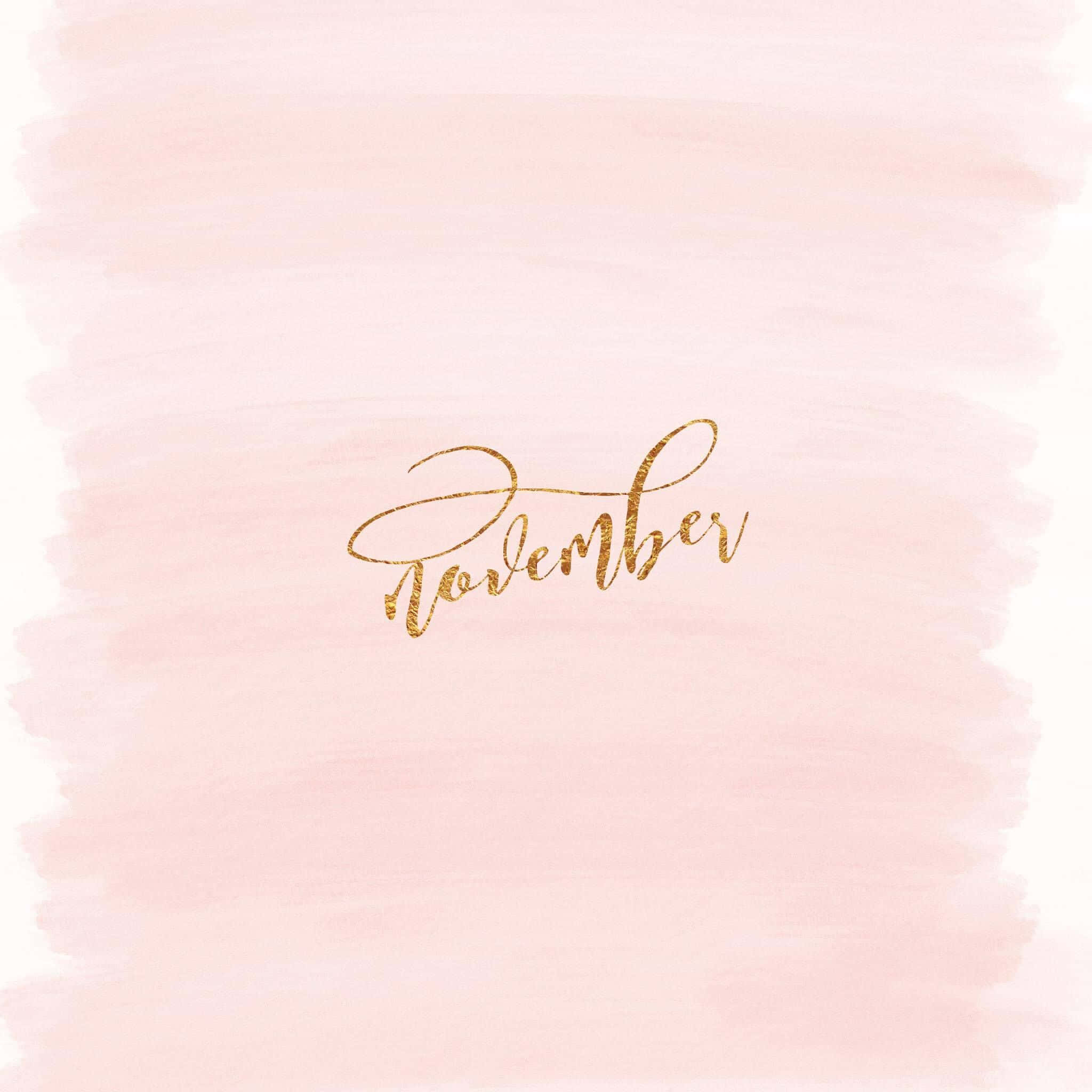 十一月 桌布 壁紙 — 閃閃發光的金色草書單詞「november」漂浮在柔和的粉紅色水彩洗滌背景上。