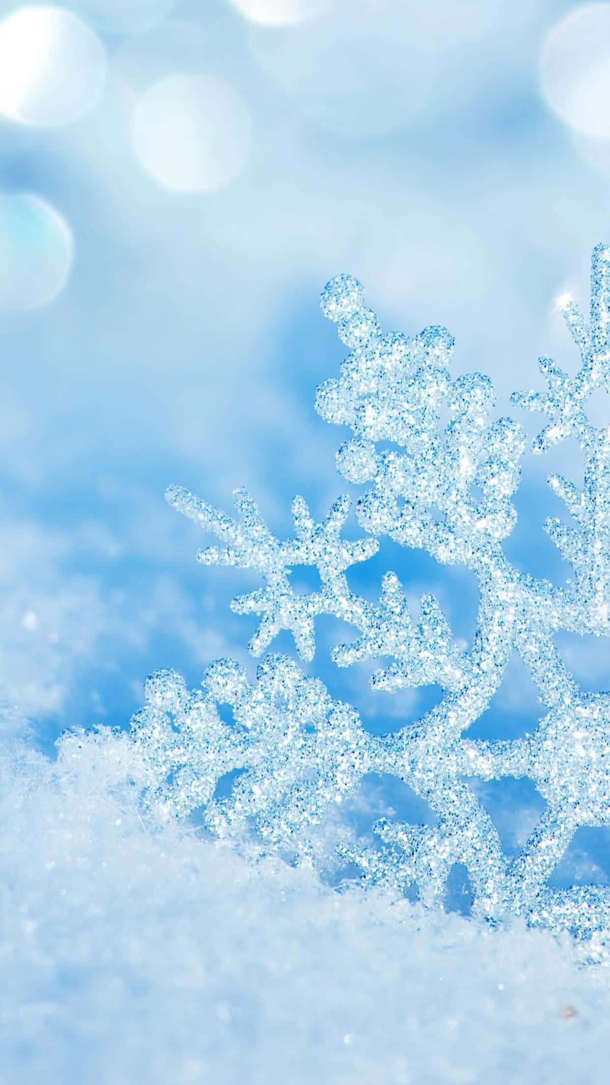 Simple Winter 桌布 壁紙 — 閃閃發光的雪花落在柔軟的雪地上，背景是夢幻的藍色散景。
