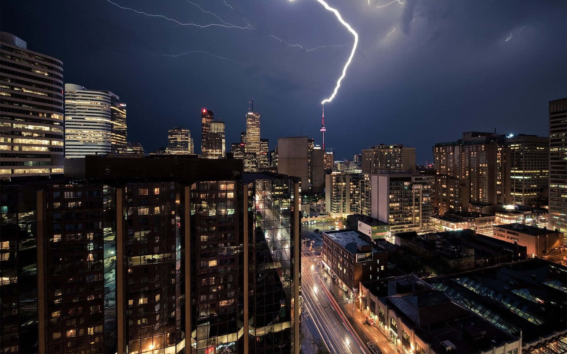 Toronto 桌布 壁紙 — 閃電擊中照亮摩天大樓和發光街道的戲劇性夜景城市景觀。