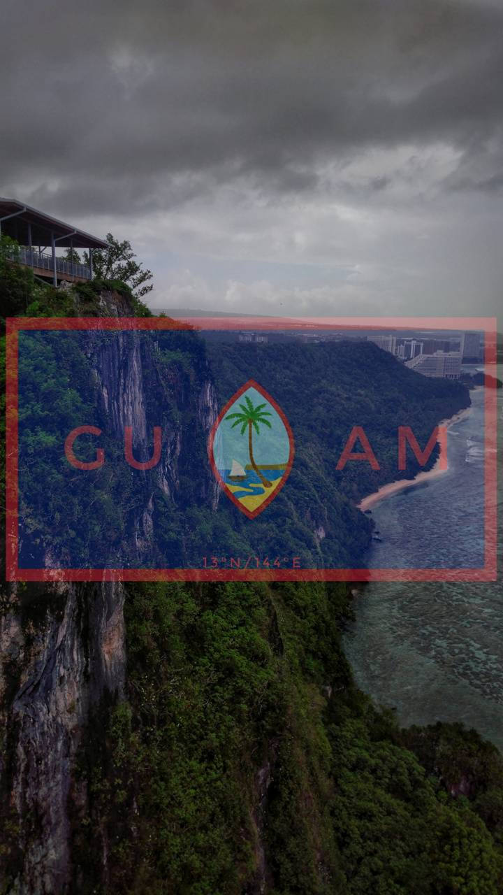 Guam 桌布 壁紙 — 關島鬱蔥的綠色懸崖俯瞰熱帶海灘和城市，在暴風雨的天空下，戲劇性的鳥瞰圖。