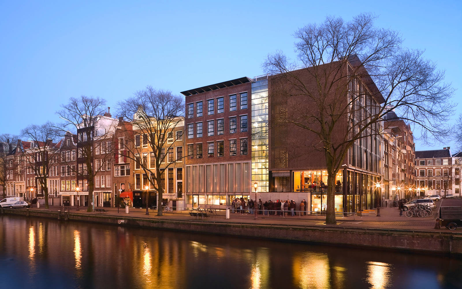Netherlands 桌布 壁紙 — 阿姆斯特丹的暮色運河場景，歷史建築與現代玻璃建築在水面上反射溫暖燈光。