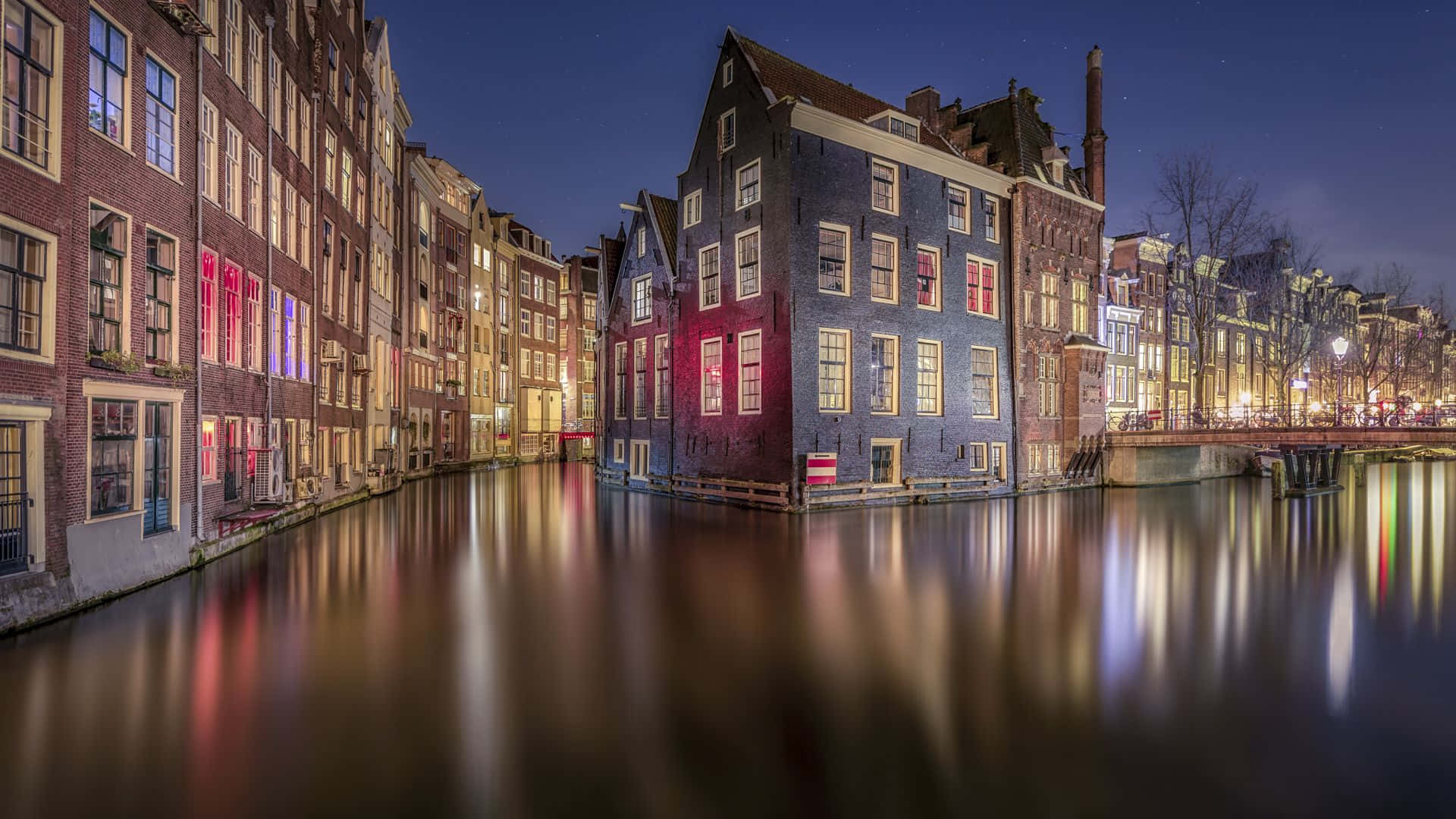 鎖屏 桌布 壁紙 — 阿姆斯特丹運河的寧靜夜景，歷史建築在星空下將溫暖燈光倒映在平靜的水面上。