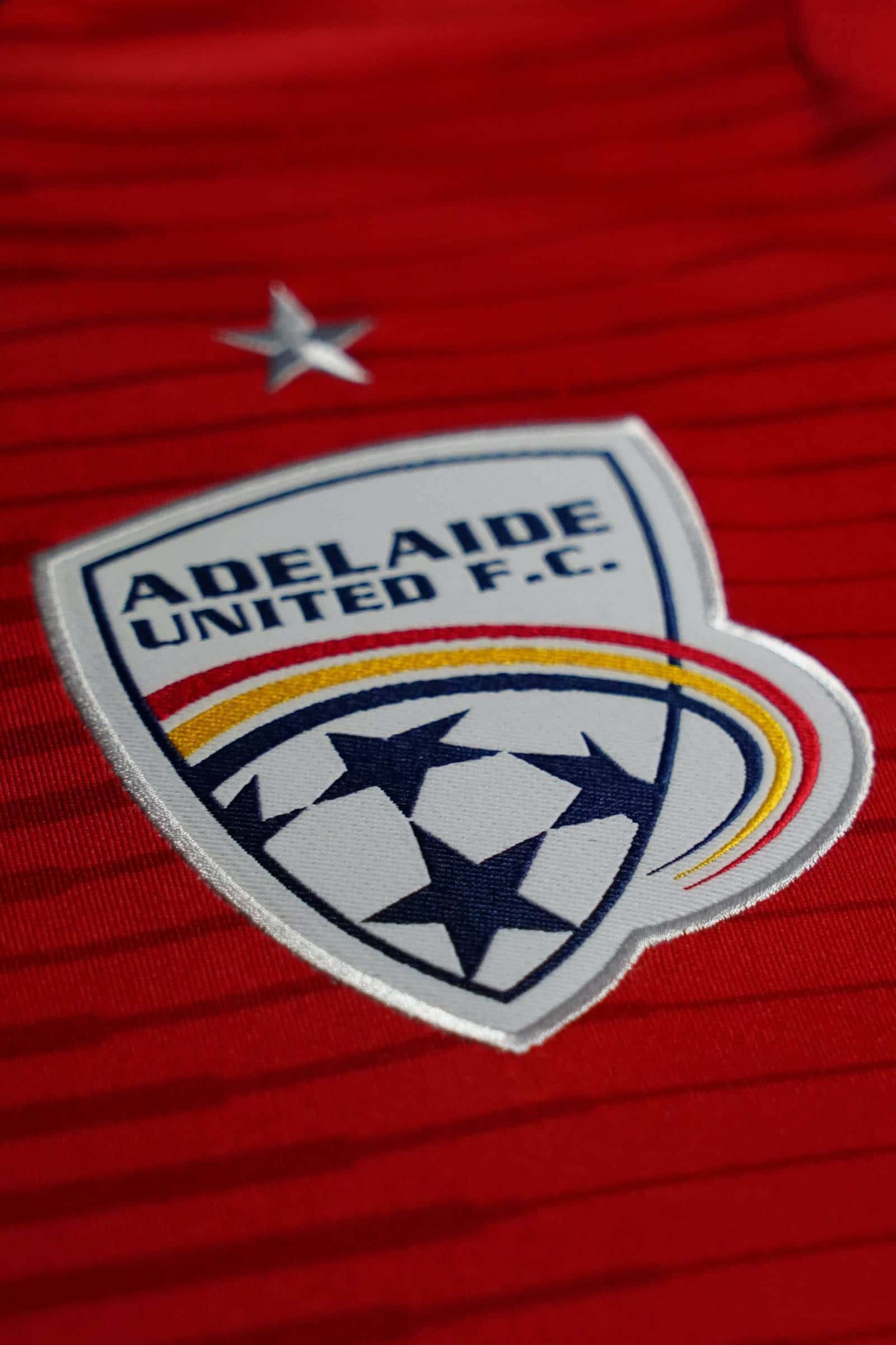 Adelaide United 桌布 壁紙 — 阿德萊德聯足球俱樂部徽章近距離特寫，繡在帶有紋理的紅色足球球衣上，上方有一顆銀星。
