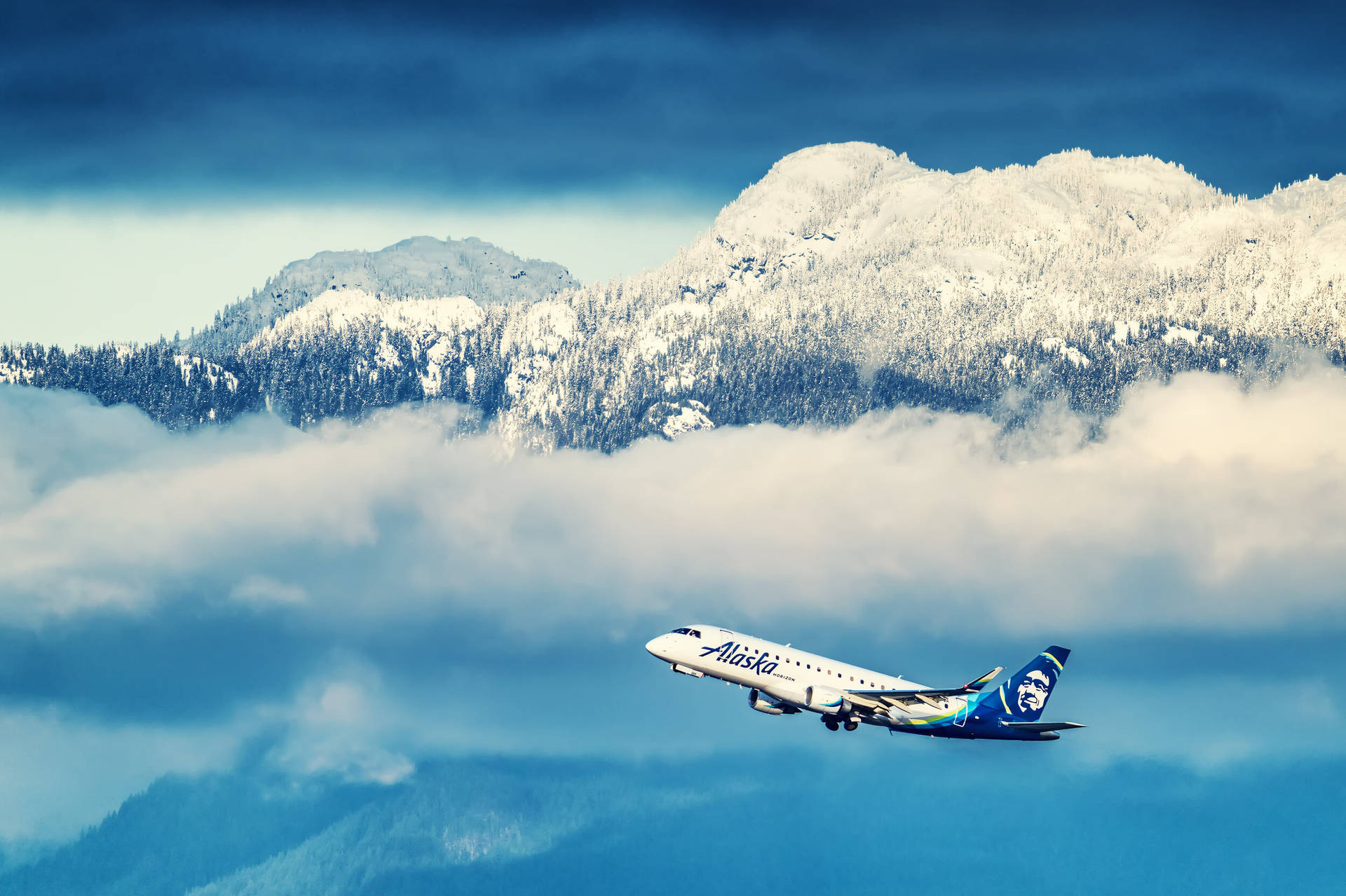 飛機 桌布 壁紙 — 阿拉斯加航空的飛機在雲海上翱翔，背景是白雪覆蓋的山峰。