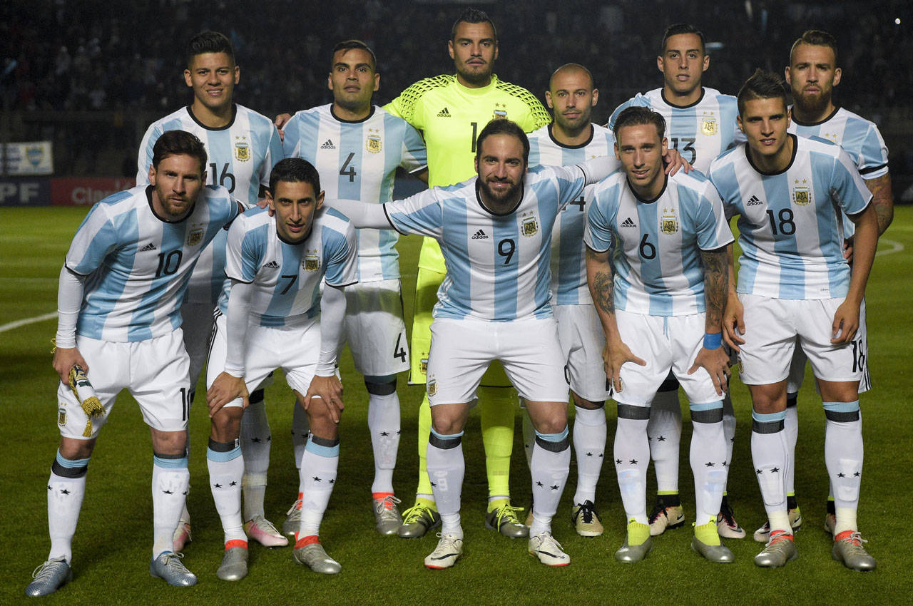 Argentina 桌布 壁紙 — 阿根廷國家足球隊在球場燈光下，身穿淺藍色和白色條紋球衣，在綠色草地上擺姿勢。