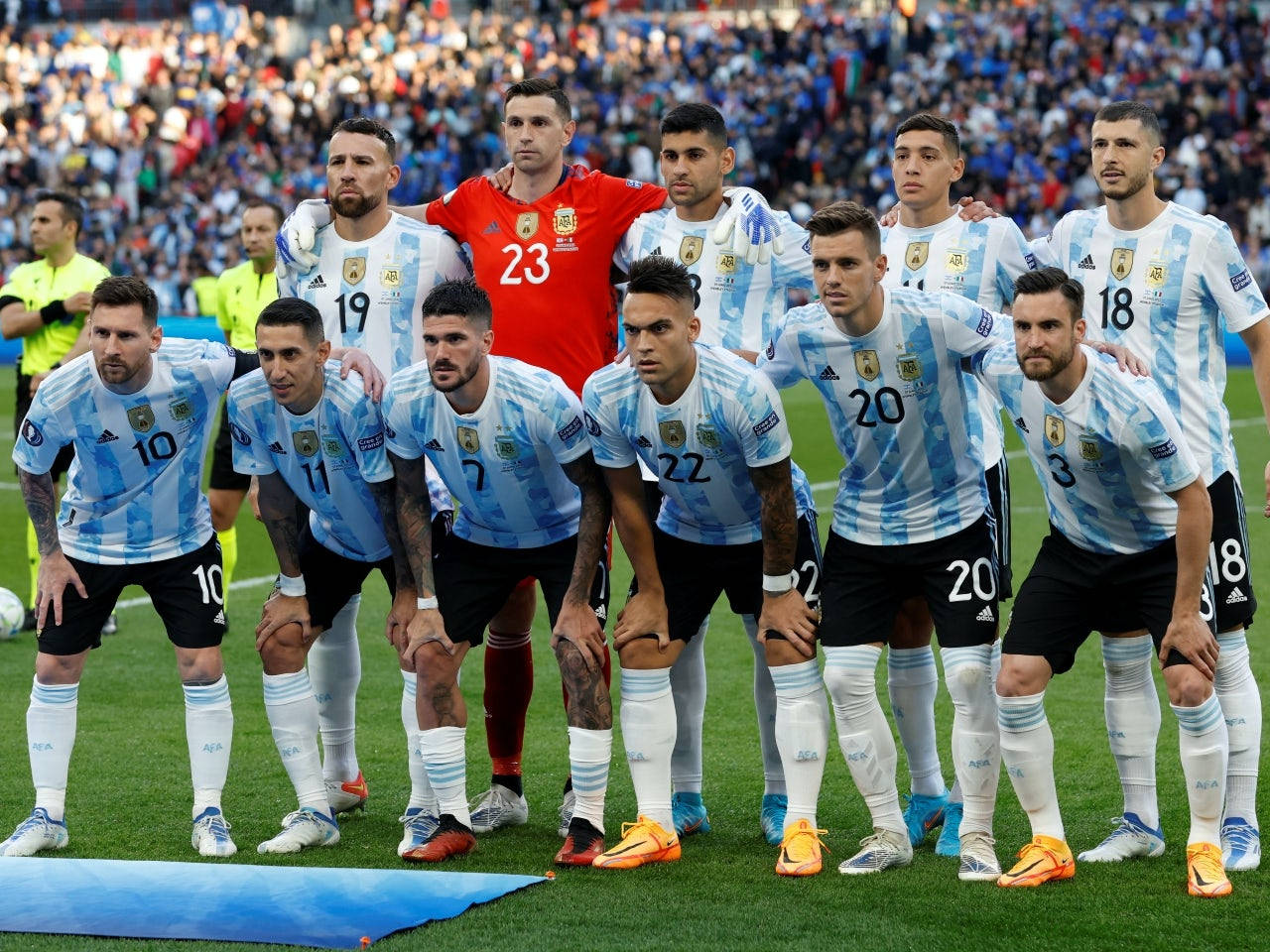 Argentina 桌布 壁紙 — 阿根廷國家足球隊身穿淺藍色和白色條紋球衣，在擠滿觀眾的體育館前，於充滿活力的綠色球場上擺姿勢。