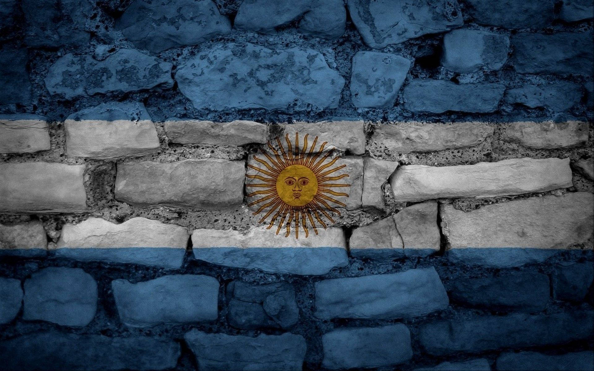 Argentina 桌布 壁紙 — 阿根廷國旗繪在風化的石牆上，帶有藍白條紋和金色太陽標誌。