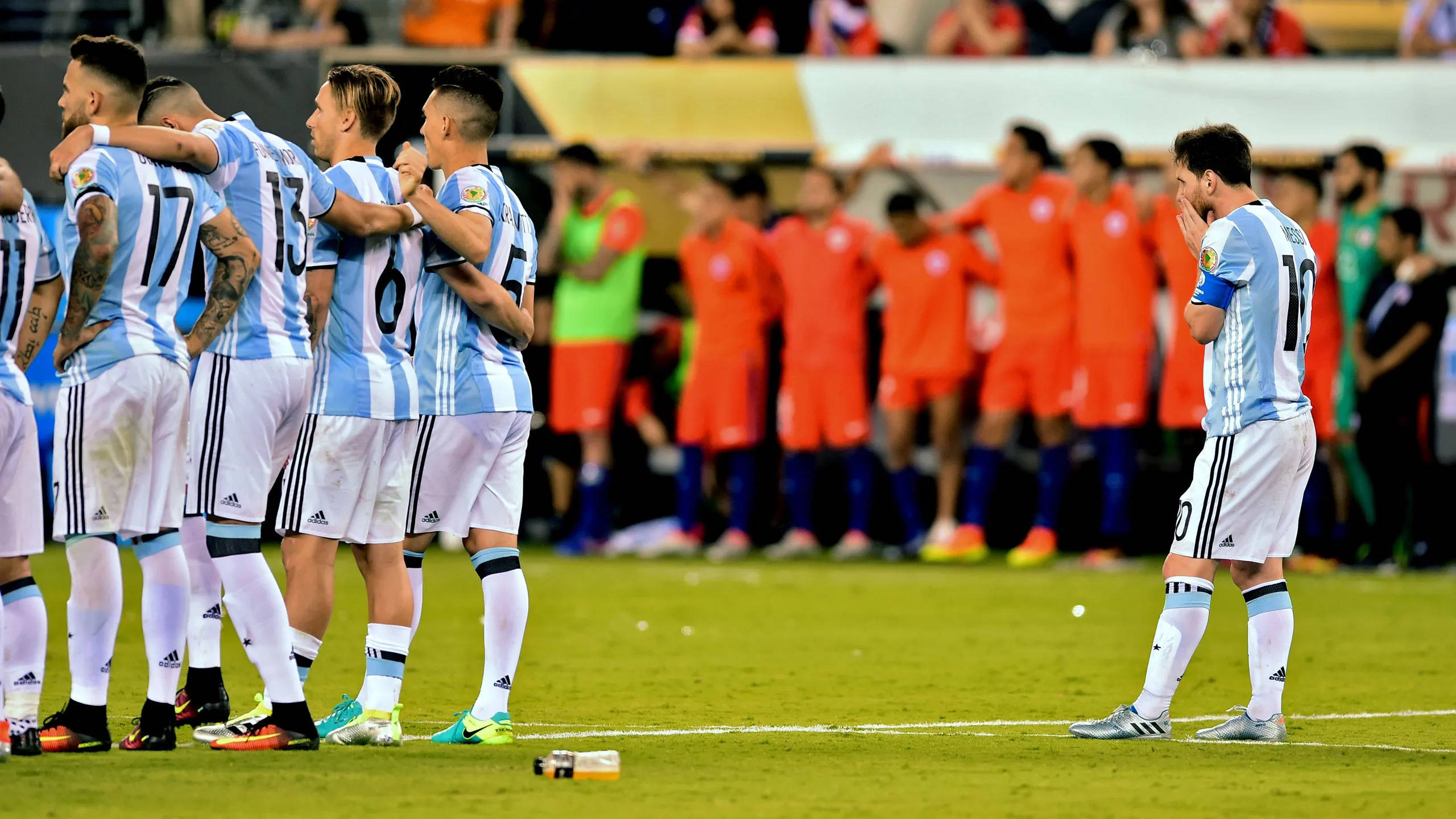 Argentina 桌布 壁紙 — 阿根廷足球員身穿藍白球衣在綠色球場上聚在一起，而一名球員獨自站著低頭看。