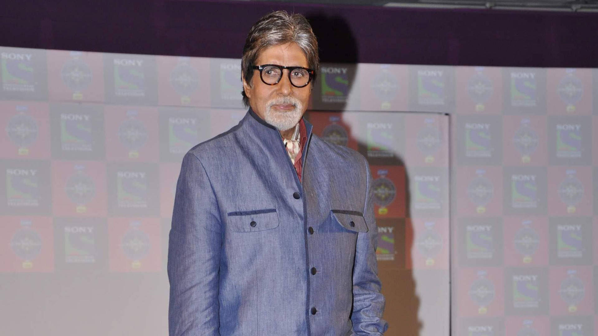 Amitabh Bachchan 桌布 壁紙 — 阿米塔布·巴強在活動中自信地穿著藍色紋理外套，站在Sony品牌背景前。