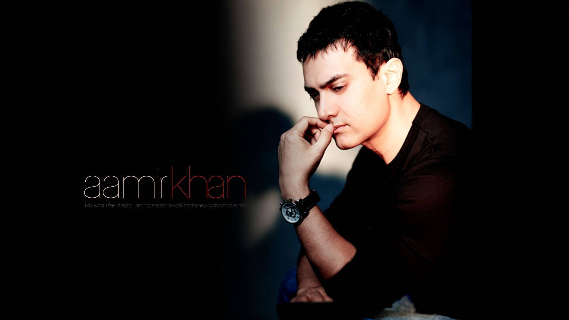 Aamir Khan 桌布 壁紙 — 阿米爾·汗在陰暗氛圍的背景前，以柔和光線凸顯臉部和手部的沉思姿態。