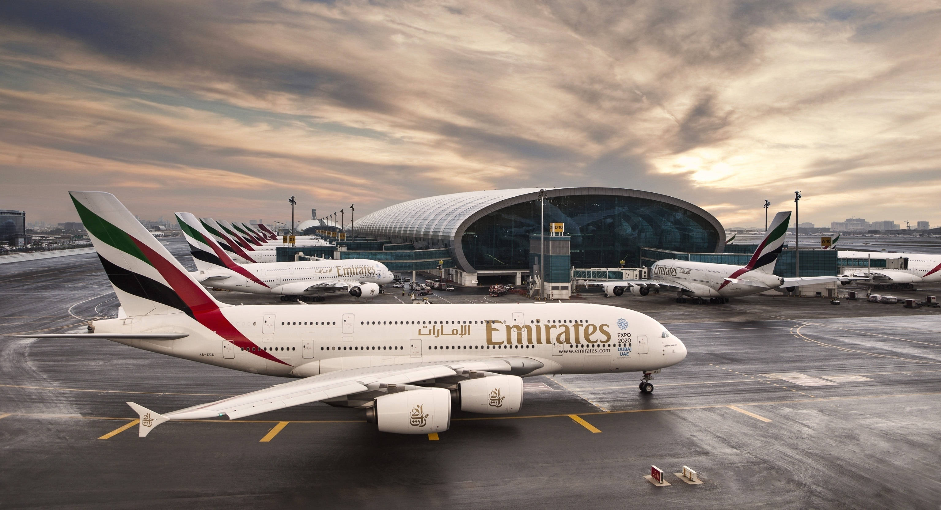 Airport 桌布 壁紙 — 阿聯酋航空的空中巴士A380在戲劇性的黃金時段天空下，排列在機場航廈前。