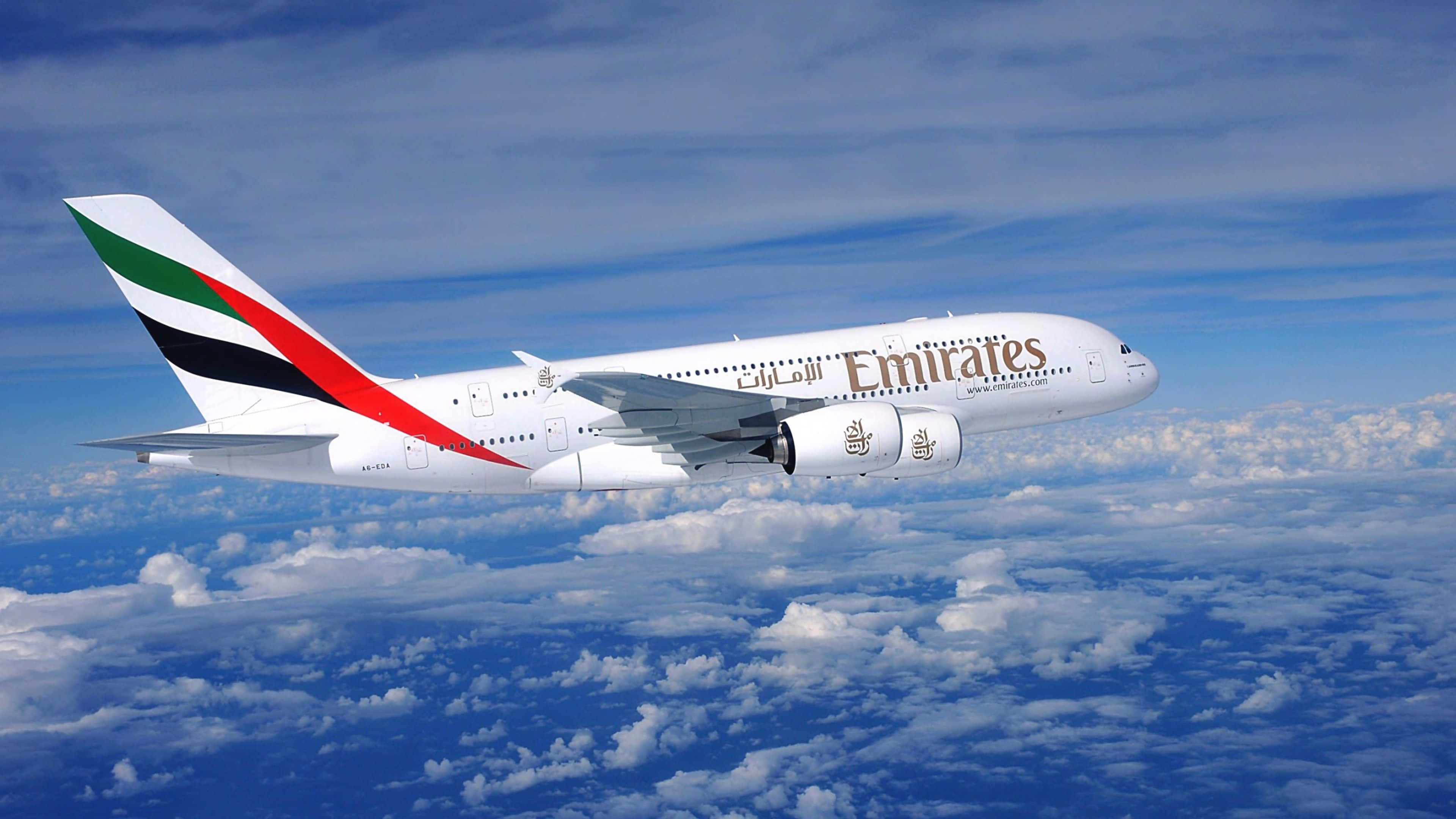 4K 桌布 壁紙 — 阿聯酋航空的空中巴士A380在湛藍天空下，優雅地翱翔於蓬鬆的白雲之上。
