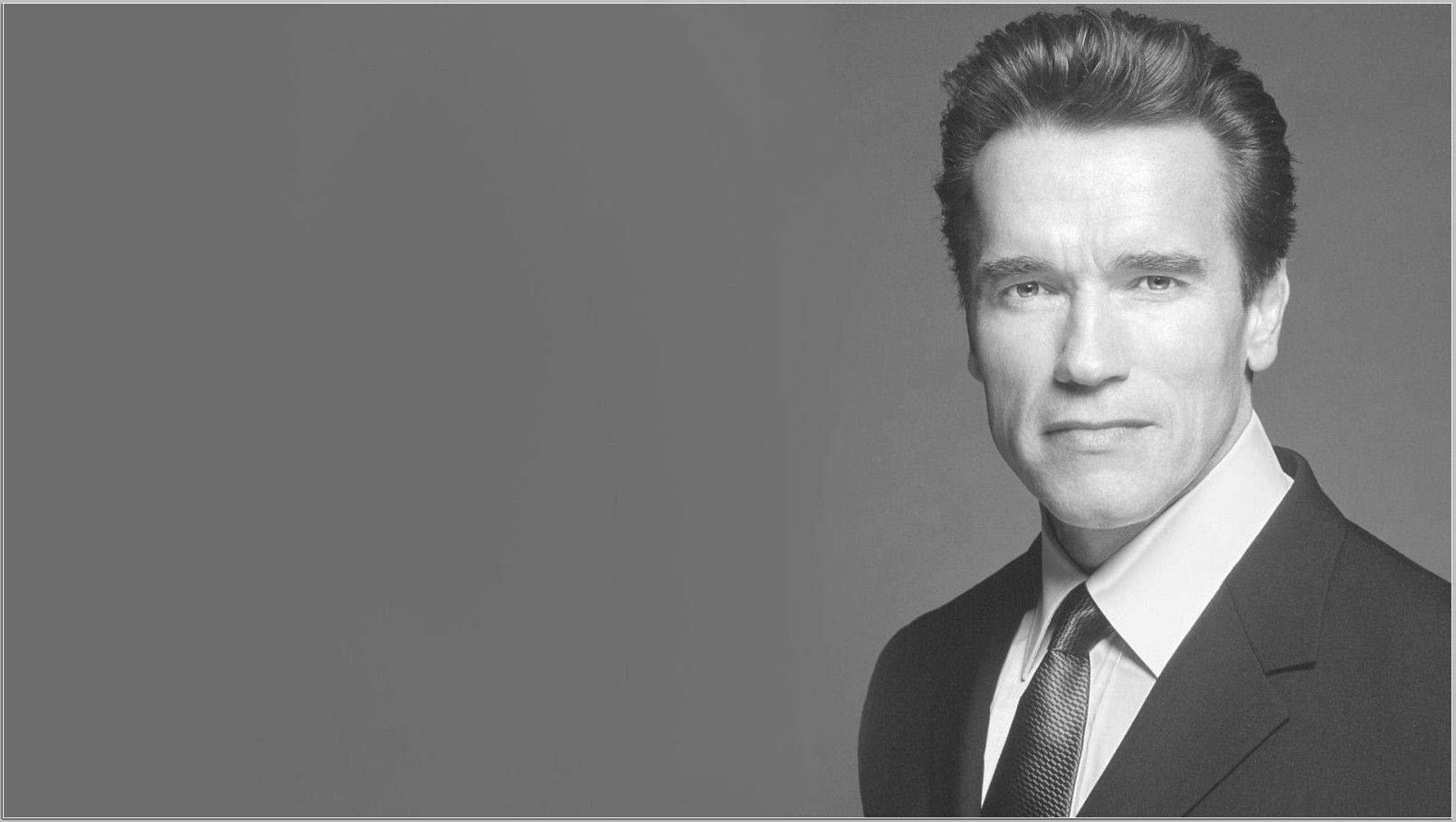 Arnold 桌布 壁紙 — 阿諾·史瓦辛格身穿西裝打領帶，在純灰色背景前的黑白肖像。