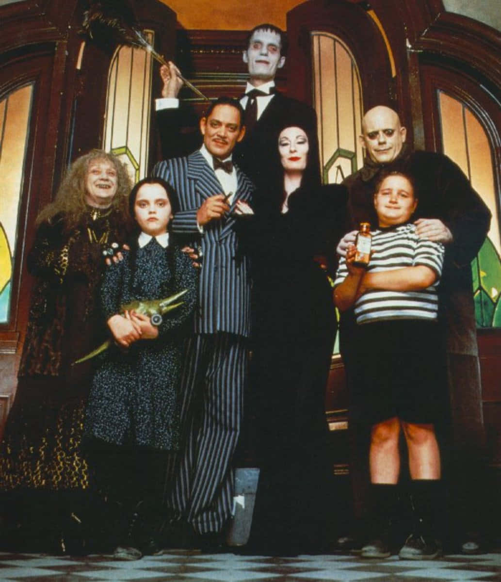 Addams Family 桌布 壁紙 — 阿達一族在他們擁有彩繪玻璃窗和棋盤地板的哥德式大宅中一起擺姿勢。