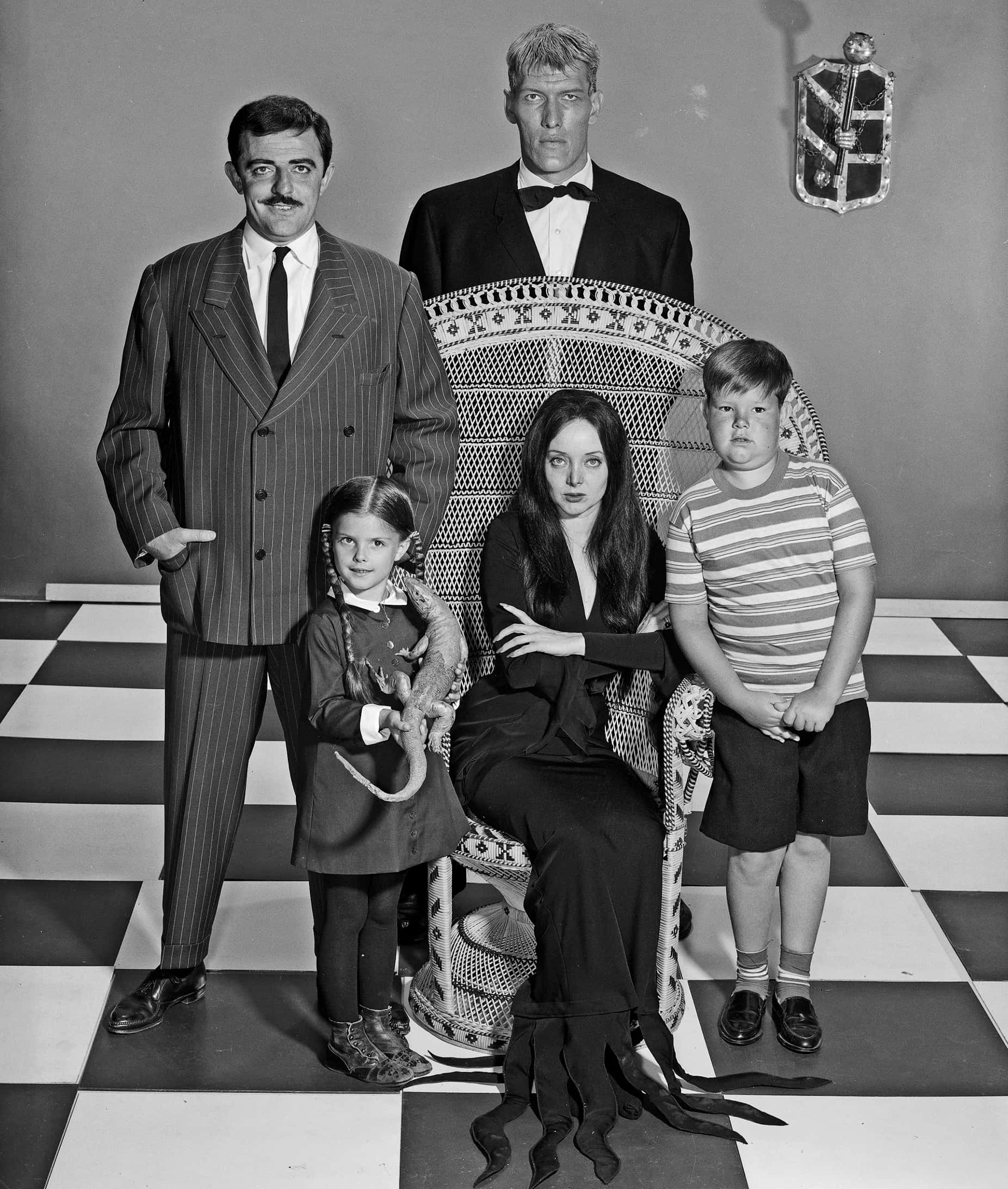 Addams Family 桌布 壁紙 — 阿達一族在棋盤格地板上的黑白家庭肖像，帶有哥德式裝飾。