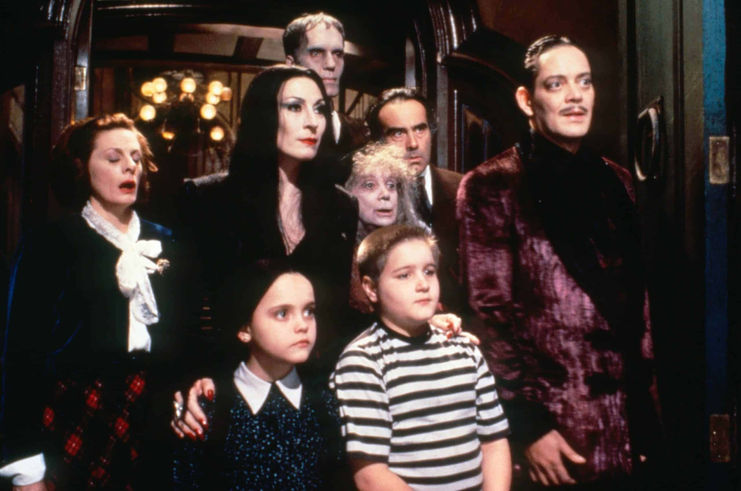 Addams Family 桌布 壁紙 — 阿達一族聚集在哥德式大宅的走廊，燈光戲劇性，裝飾華麗。