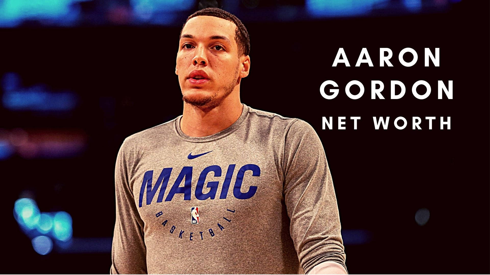aaron gordon 桌布 壁紙 — 阿隆·戈登身穿奧蘭多魔術隊訓練服，在模糊的球場背景下專注站立，帶有文字疊加。