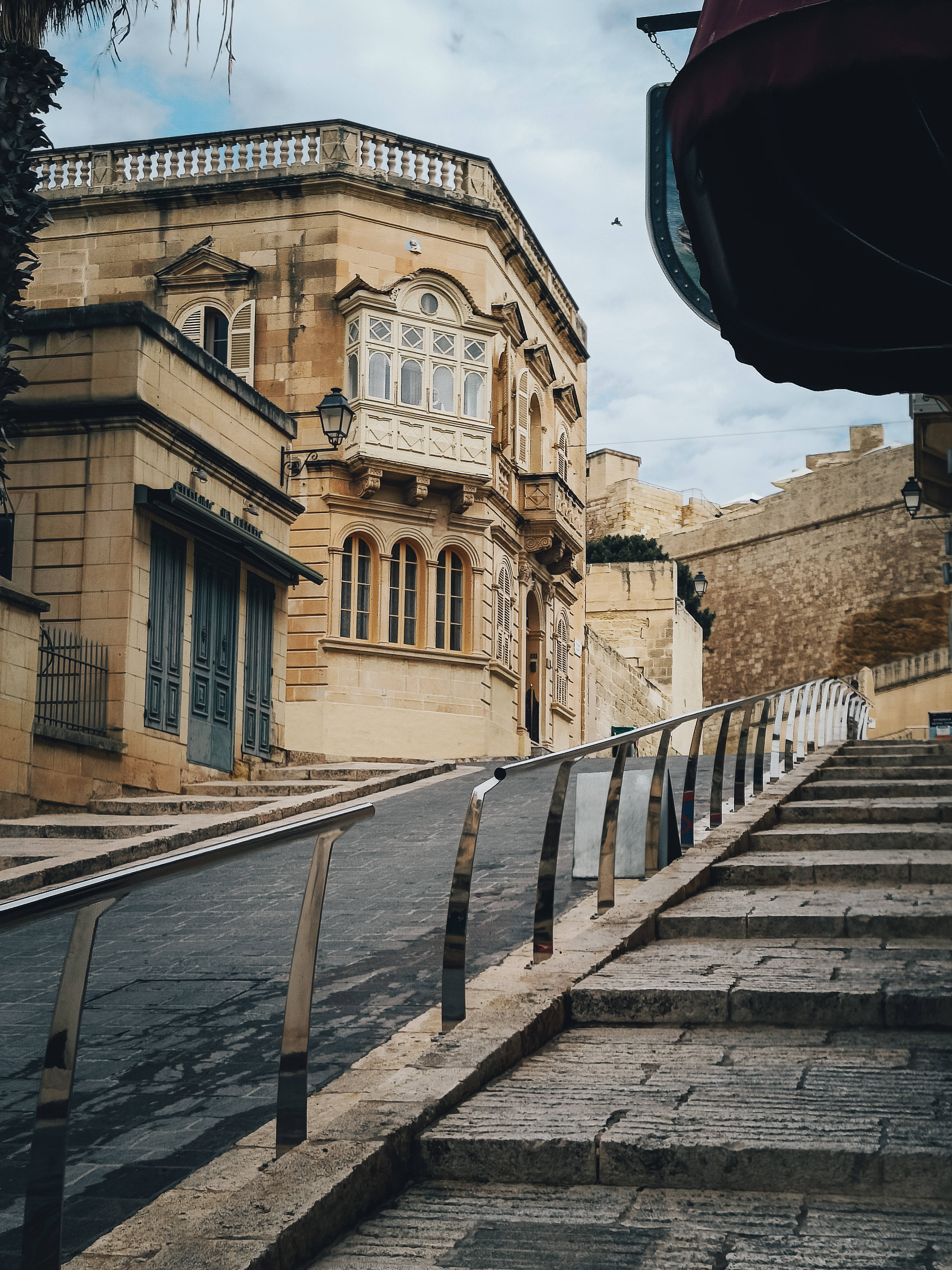 Malta 桌布 壁紙 — 陡峭的石階梯在陰天中經過歷史悠久的馬耳他建築，建築帶有華麗的陽台。