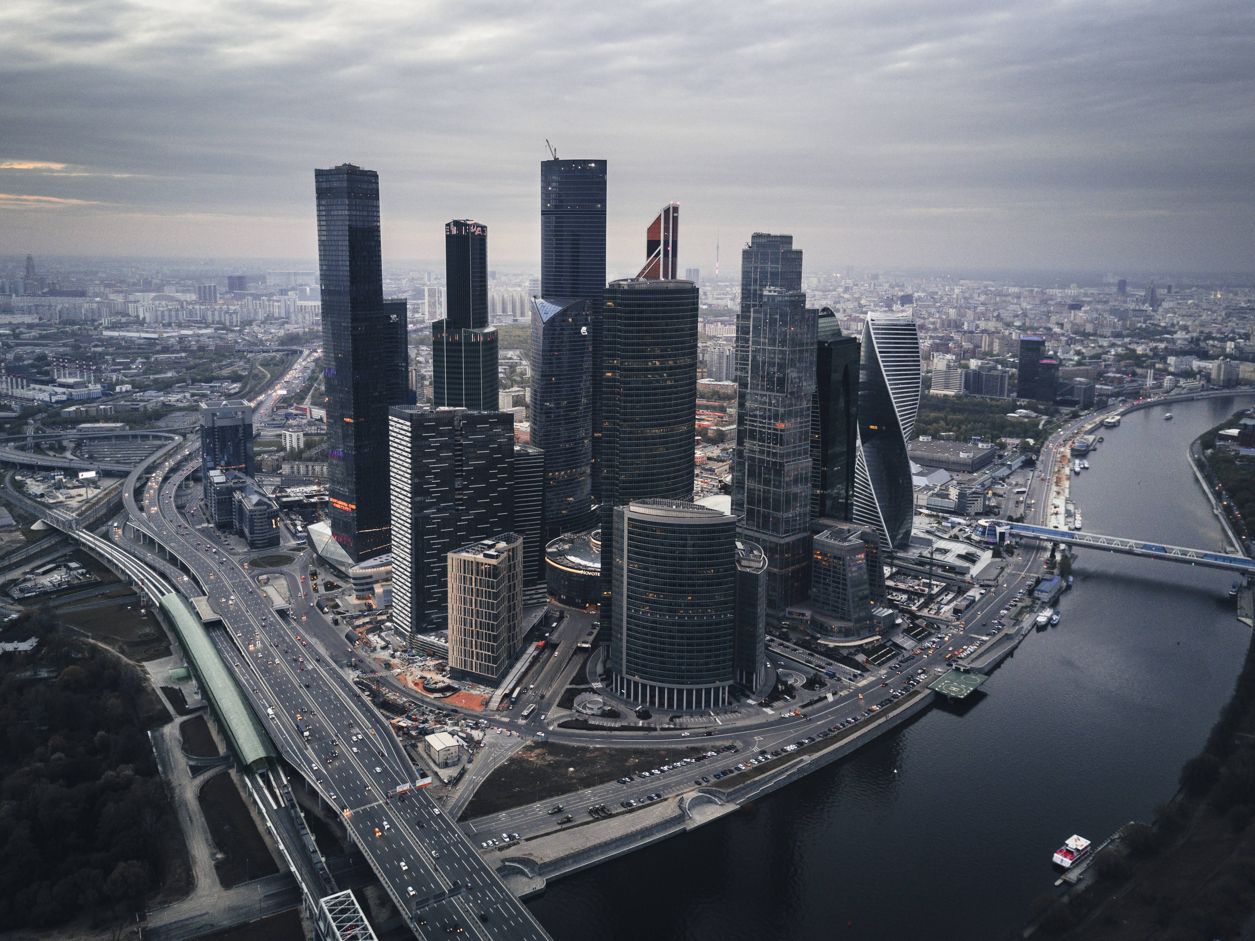 Moscow 桌布 壁紙 — 陰天下，現代玻璃摩天大樓沿河排列，繁忙高速公路的鳥瞰圖。