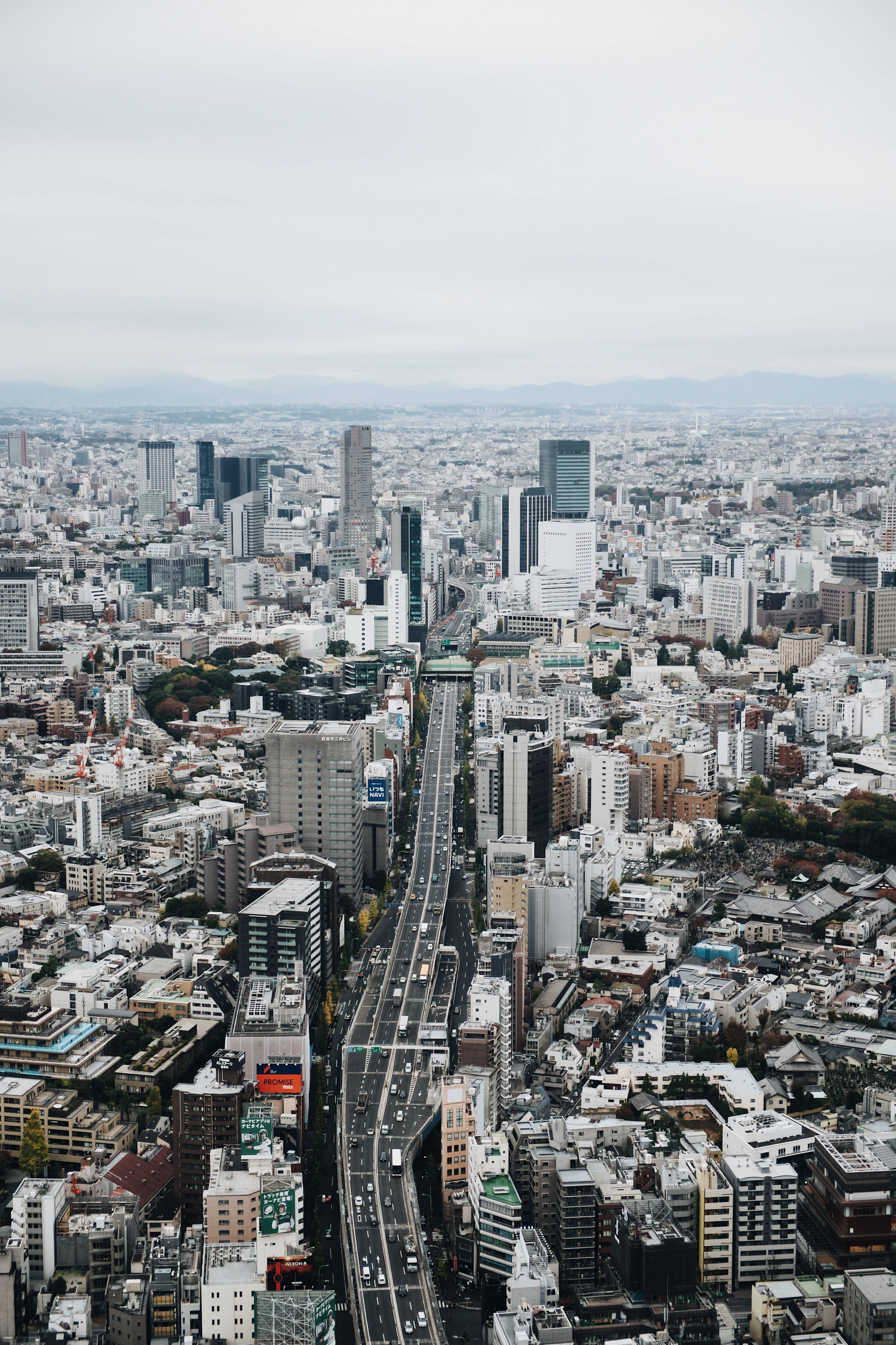 東京 桌布 壁紙 — 陰天下一片密集建築物和主要高速公路貫穿其中的廣闊城市景觀鳥瞰圖。