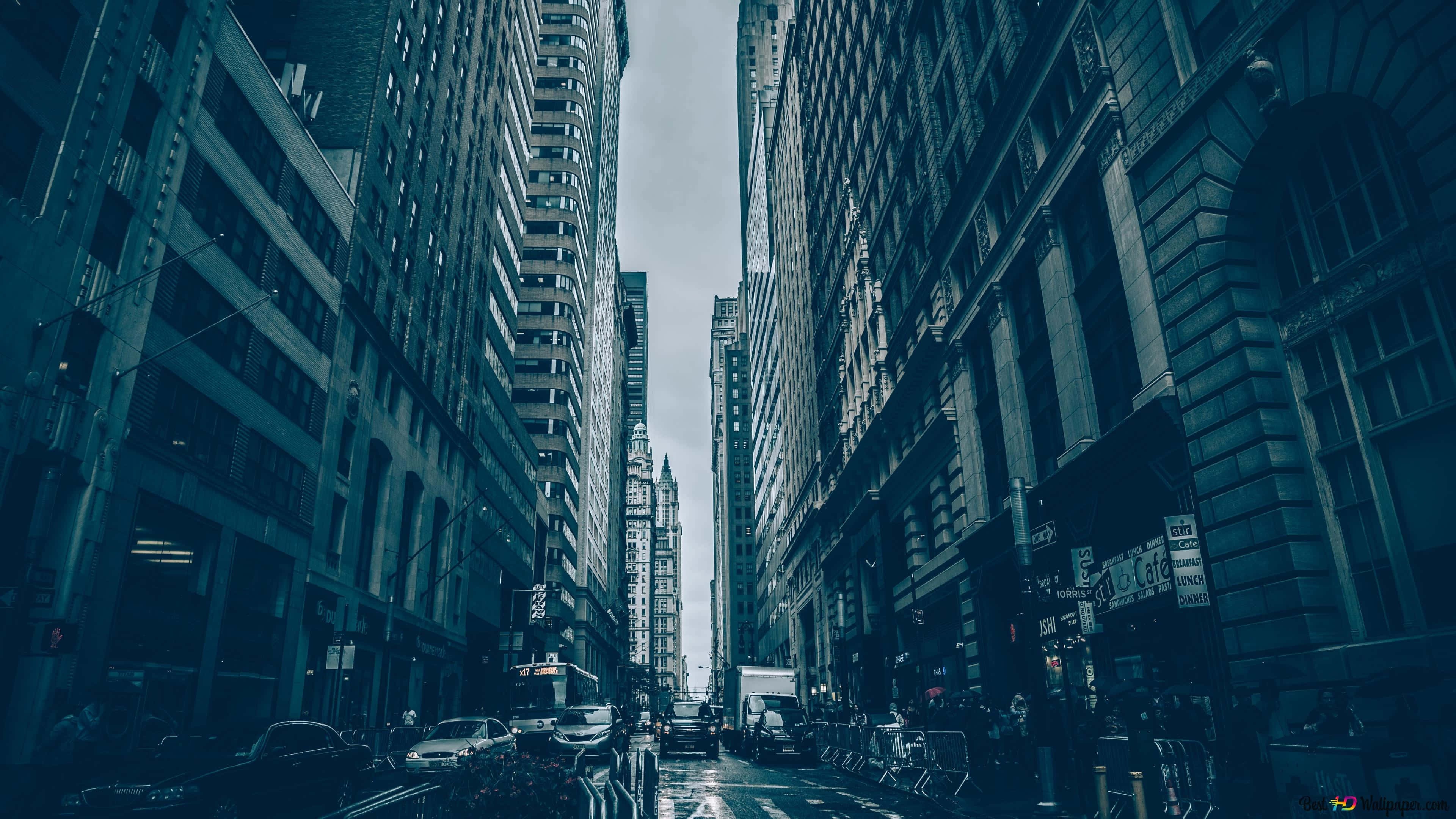 Alleyway 桌布 壁紙 — 陰沉天空下，濕漉漉的城市街道兩旁高聳摩天大樓的低角度視圖。