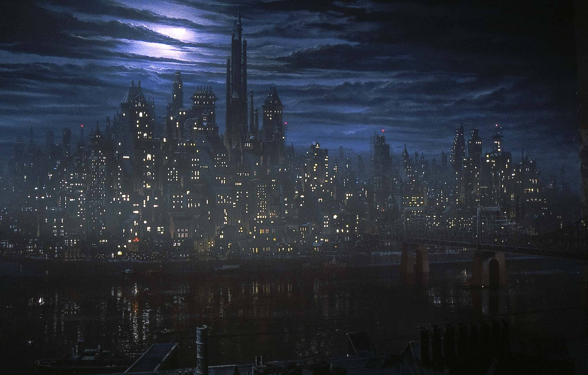 高譚 桌布 壁紙 — 陰沉的夜間城市景觀，高聳的摩天大樓在陰雲密佈的月光下，將閃爍的燈光反射在黑暗的河流上。