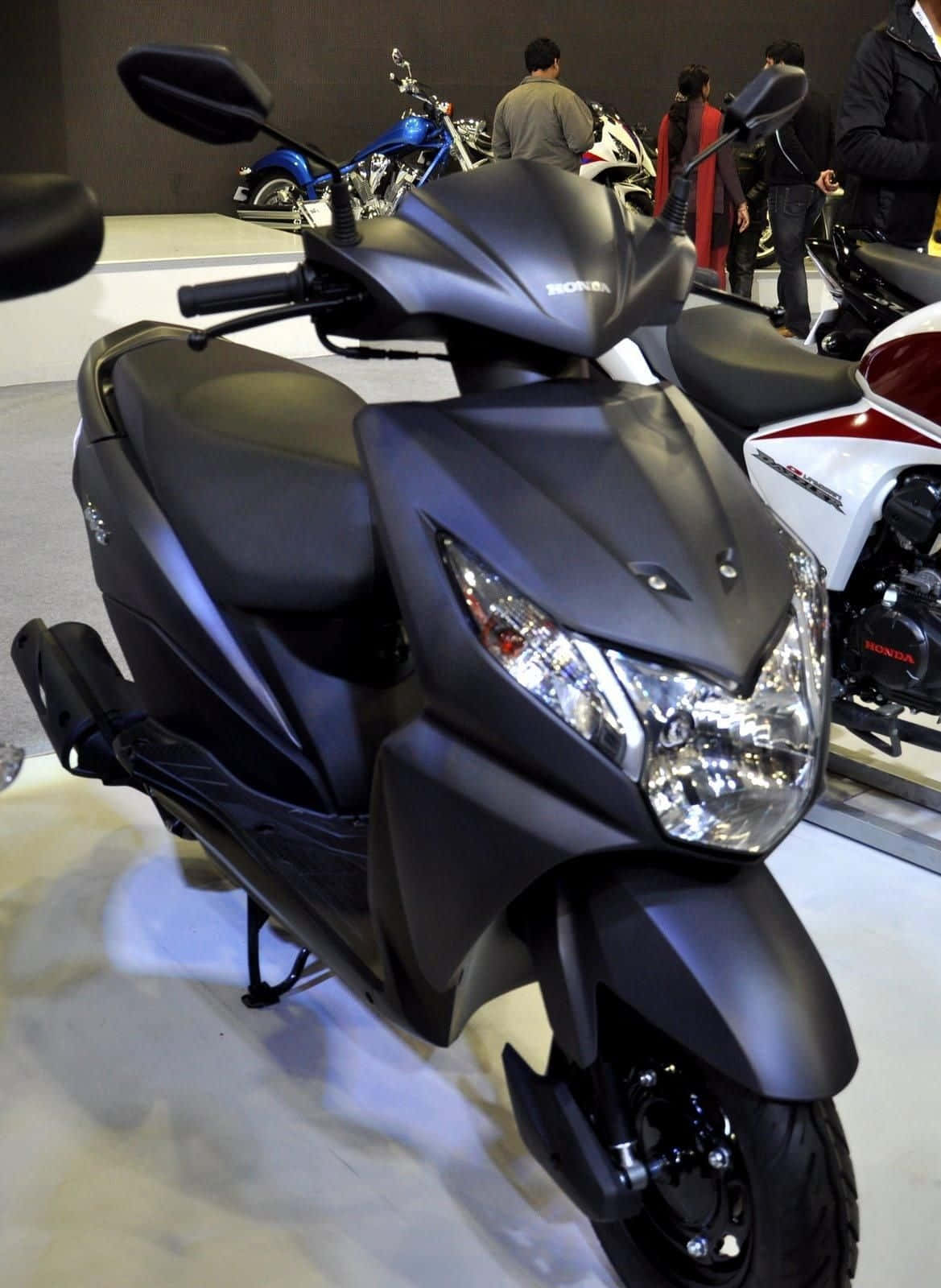 Motorcycle iPhone 桌布 壁紙 — 陳列室中展示的啞光黑色本田速克達，背景有人和其他機車。