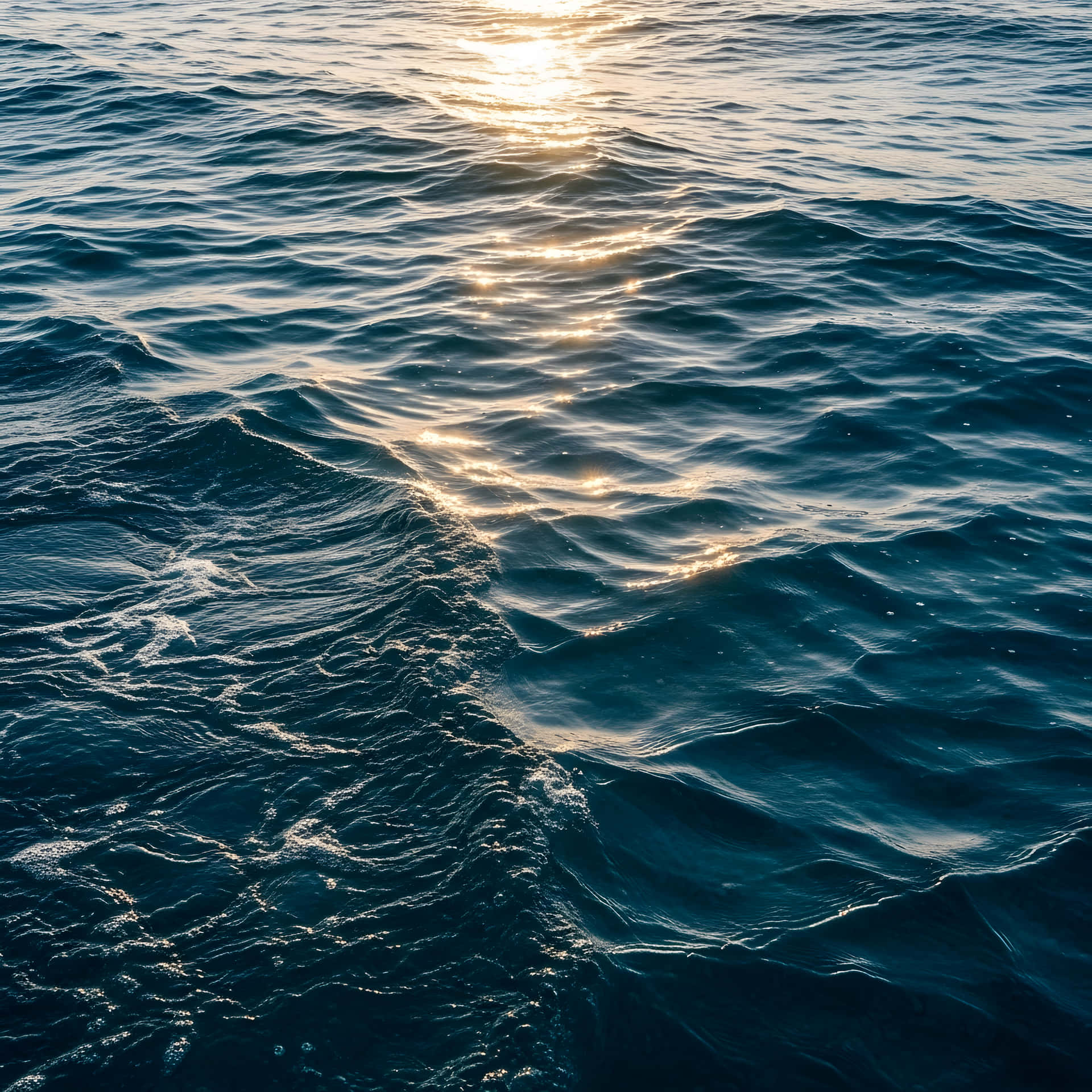 Ocean water waves 壁紙 — 陽光在寧靜的自然海景中，閃爍在紋理深邃的藍色海浪上。