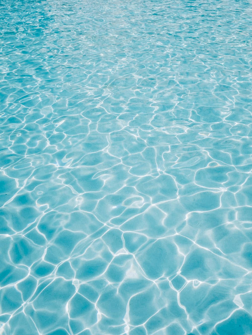Water Texture 桌布 壁紙 — 陽光在平靜泳池清澈的藍綠色水面上舞動，形成閃爍的光影圖案。