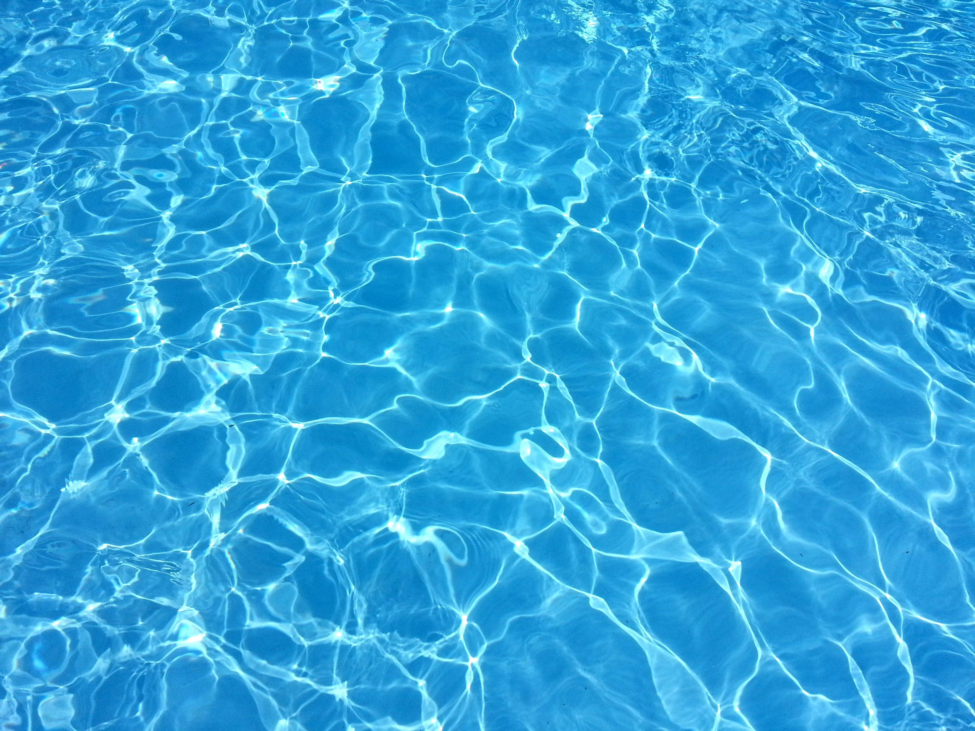 Swimming 桌布 壁紙 — 陽光在水晶般清澈的藍色水面上舞動，形成閃爍的光影圖案。
