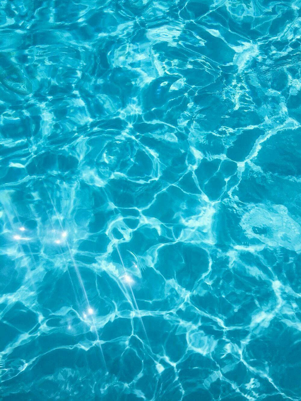 Water Aesthetic 桌布 壁紙 — 陽光在泛起漣漪的碧綠色泳池水面上舞動，形成閃爍的圖案和發光的倒影。