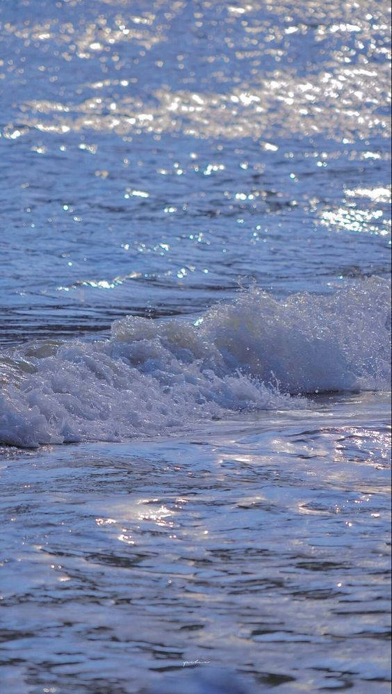 Water Aesthetic 桌布 壁紙 — 陽光在泡沫般的海浪上舞動，海浪滾滾湧上沙灘，呈現寧靜的海岸景色。