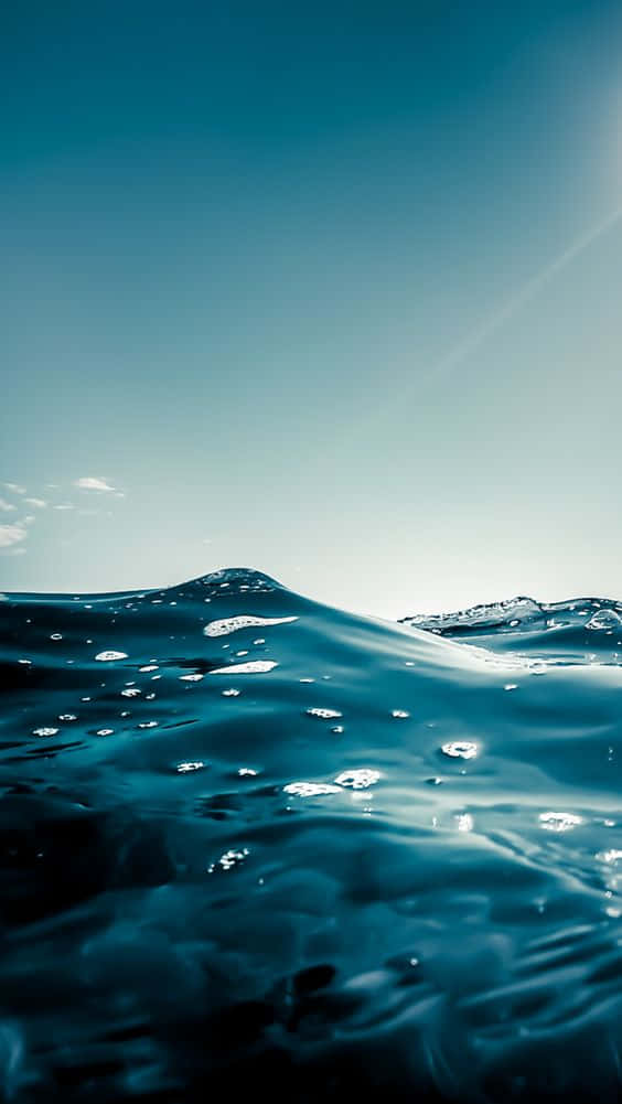 Aesthetic Wave 桌布 壁紙 — 陽光在清澈天空下閃耀在深藍色海浪上，帶有微妙的鏡頭光暈。